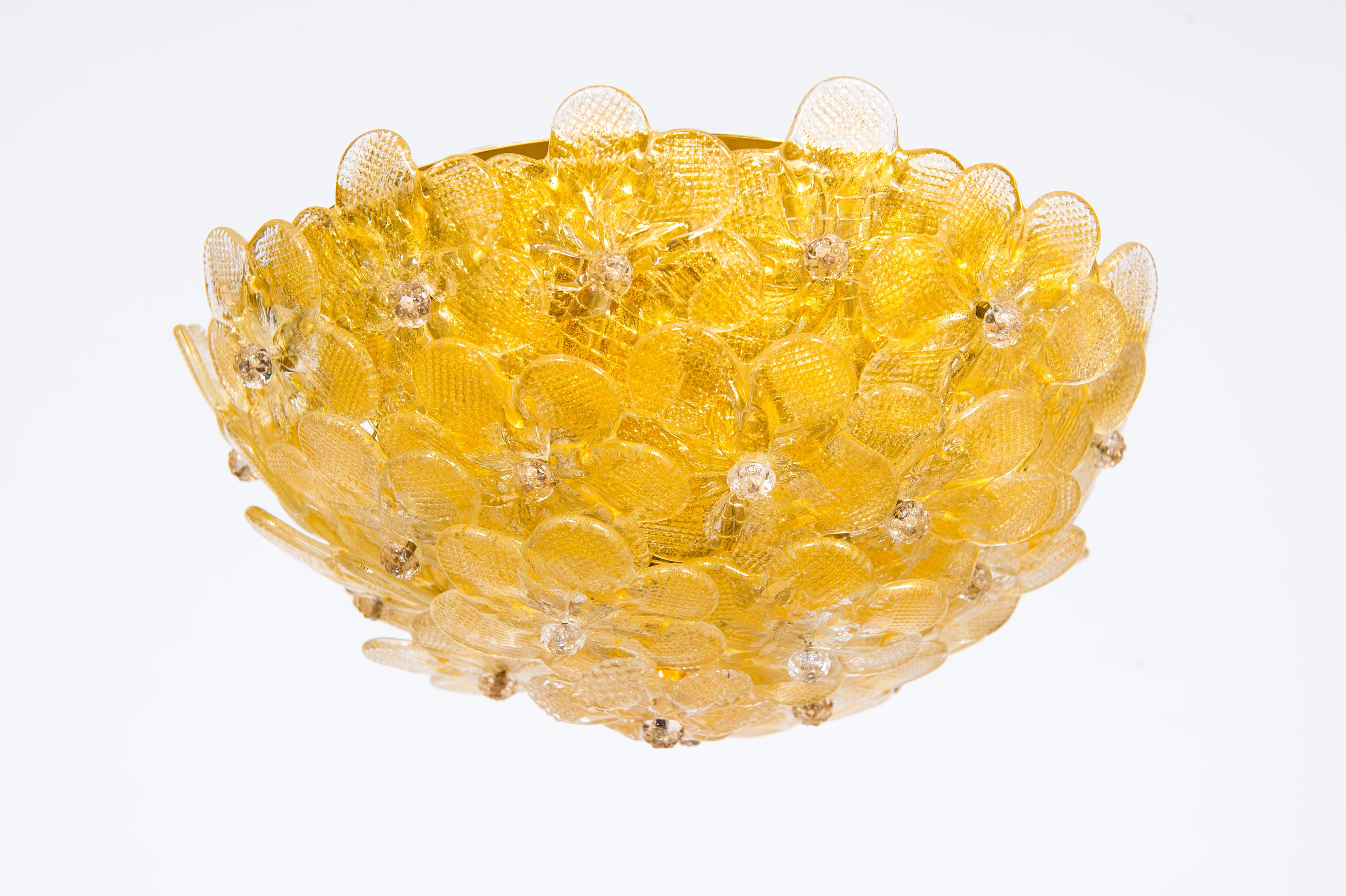 Plafonnier contemporain en verre vénitien Murano du 21e siècle avec finitions dorées.
Cette œuvre d'art étonnante se distingue par la qualité et la perfection de ses détails. Il est composé d'un ensemble de fleurs en verre qui entourent la monture