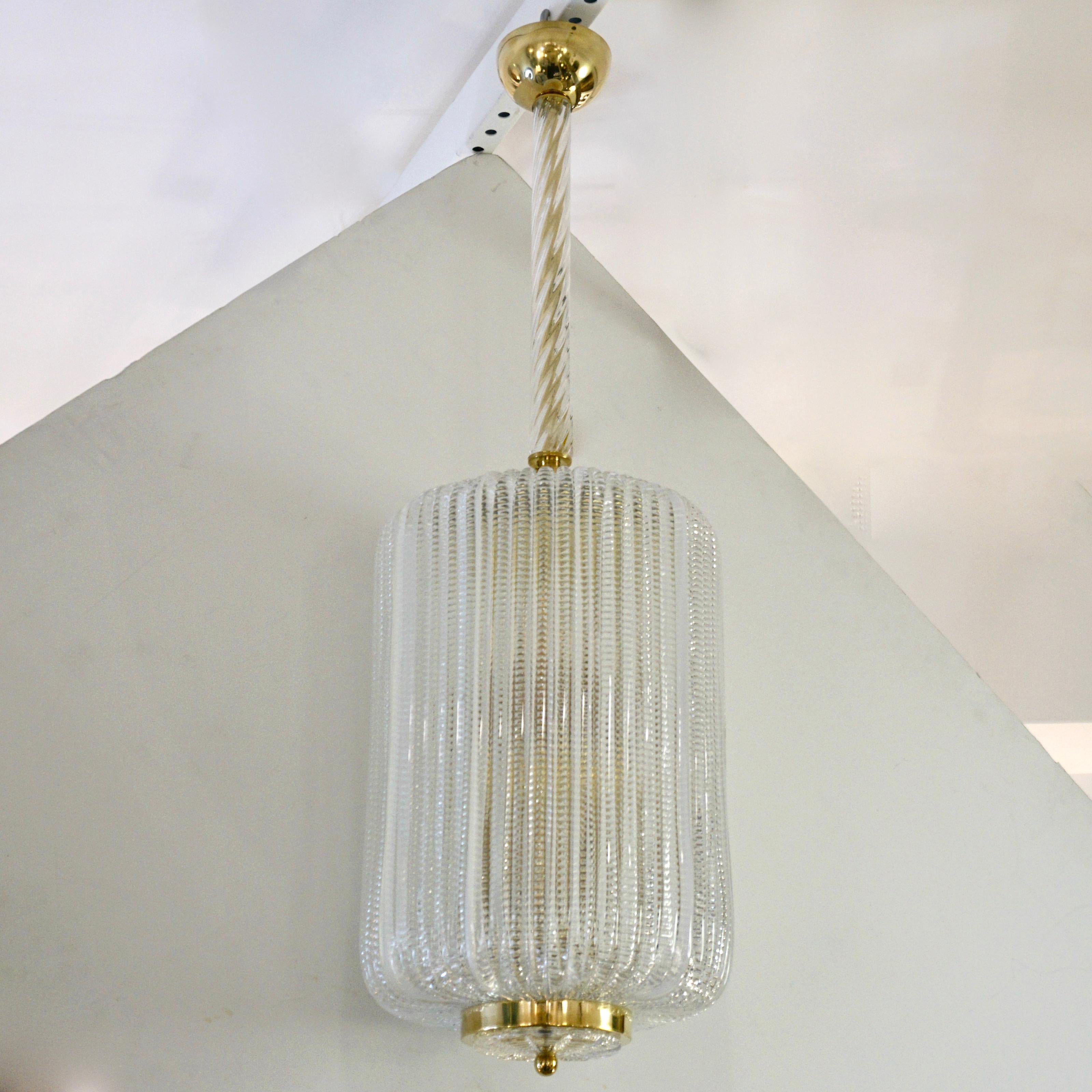 Very stylish Yet minimalist: a Venetian pendant light or chandelier, entirely handcrafted in Italy, in mid-20th century Mazzega style, with an oval cylindrical shape closed at top and bottom with brass covers, consisting of precious textured crystal