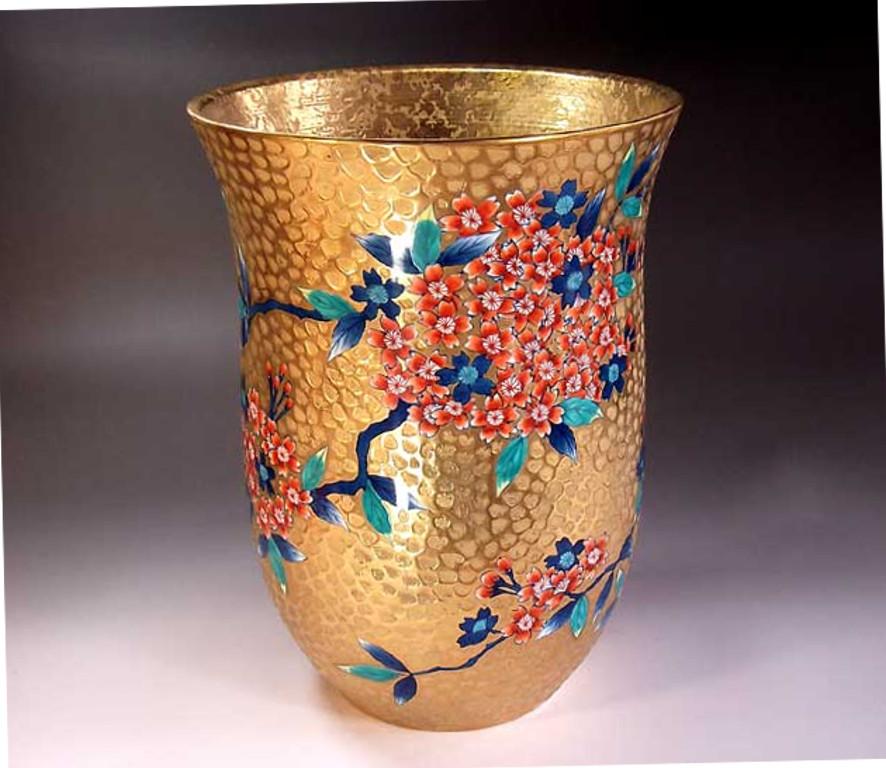 Exquisite gilded and dimpled Japanese porcelain vase intricately hand-painted to showcase cherry blossoms in iron red on a beautifully shaped body, is a signed work by widely respected master porcelain artist in Imari-Arita style. In 2016, the