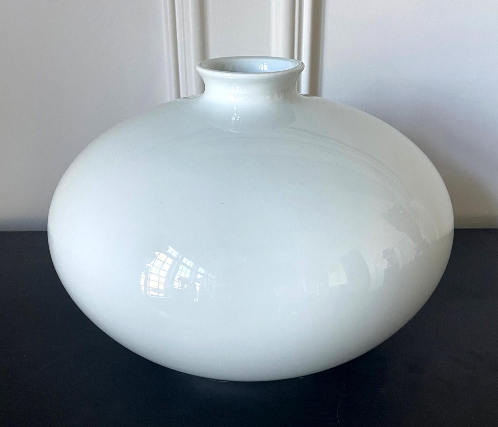 A large glazed white porcelain vase in the jar-form by Japanese ceramic artist Inoue Manji (Japanese, b. 1929). Minimalistic in form, the vase is pure white with a very subtle blue hue and of a perfect nearly sphere form. It has a small mouth
