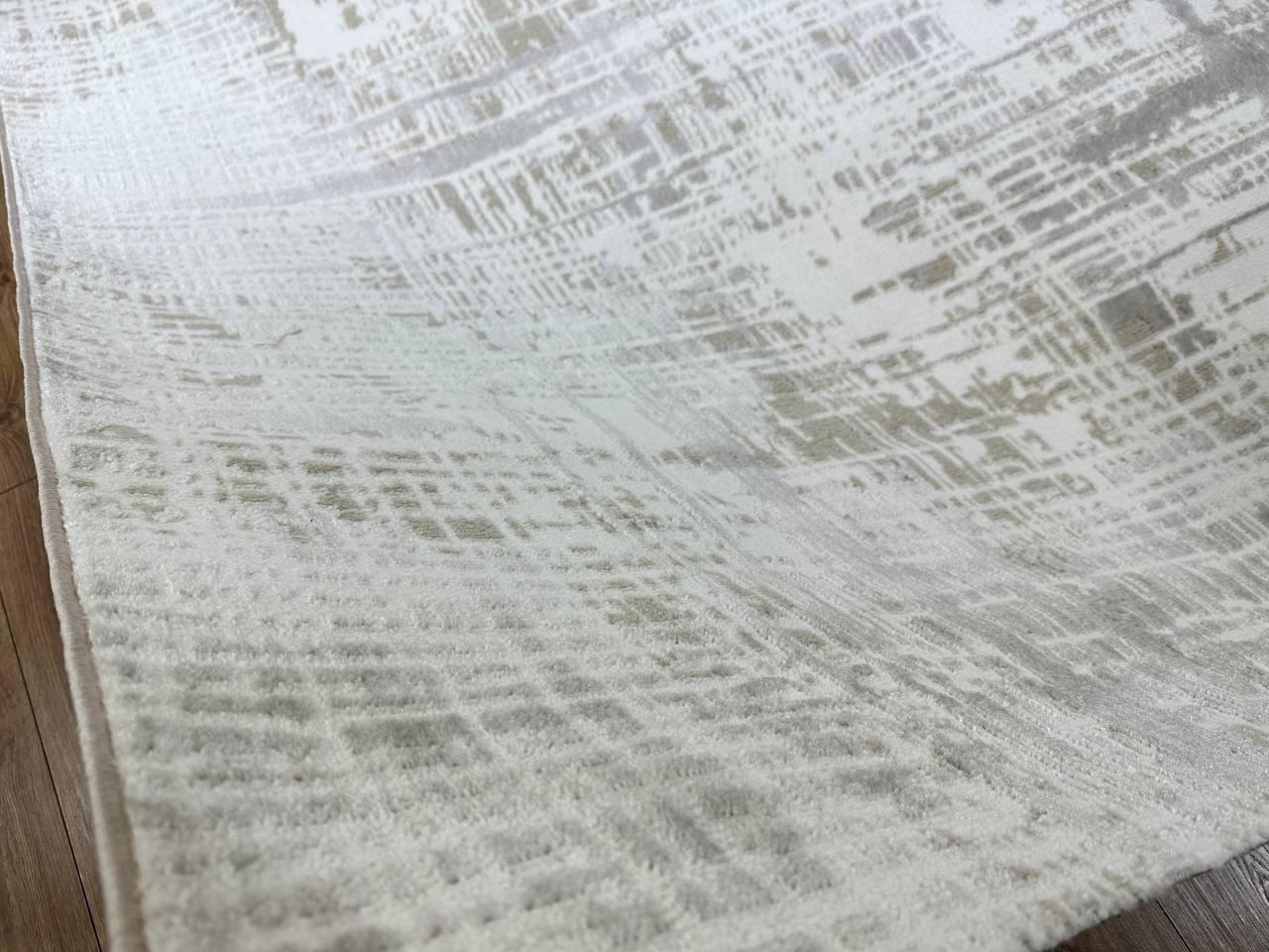This contemporary Kazakh rug features a modern design with an abstract solid pattern, crafted from a blend of cotton, polyester, and polypropylene. The elegant white and gray colors make this lightweight, machine-made rug a versatile addition to any