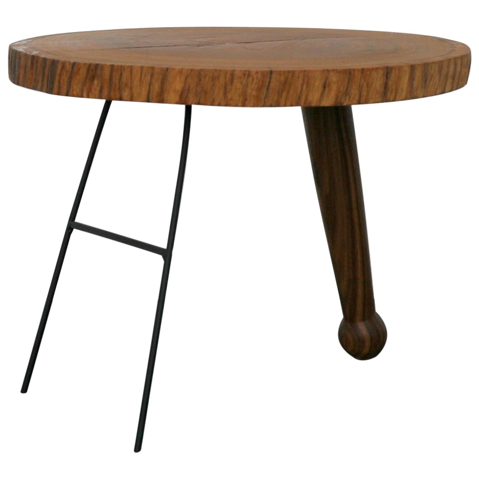 Kiaat wood and steel. Kiaat table top: tree trunk cut to 55mm thickness. Single leg of turned Kiaat, oiled with pure linseed oil, and additional coated steel supports.