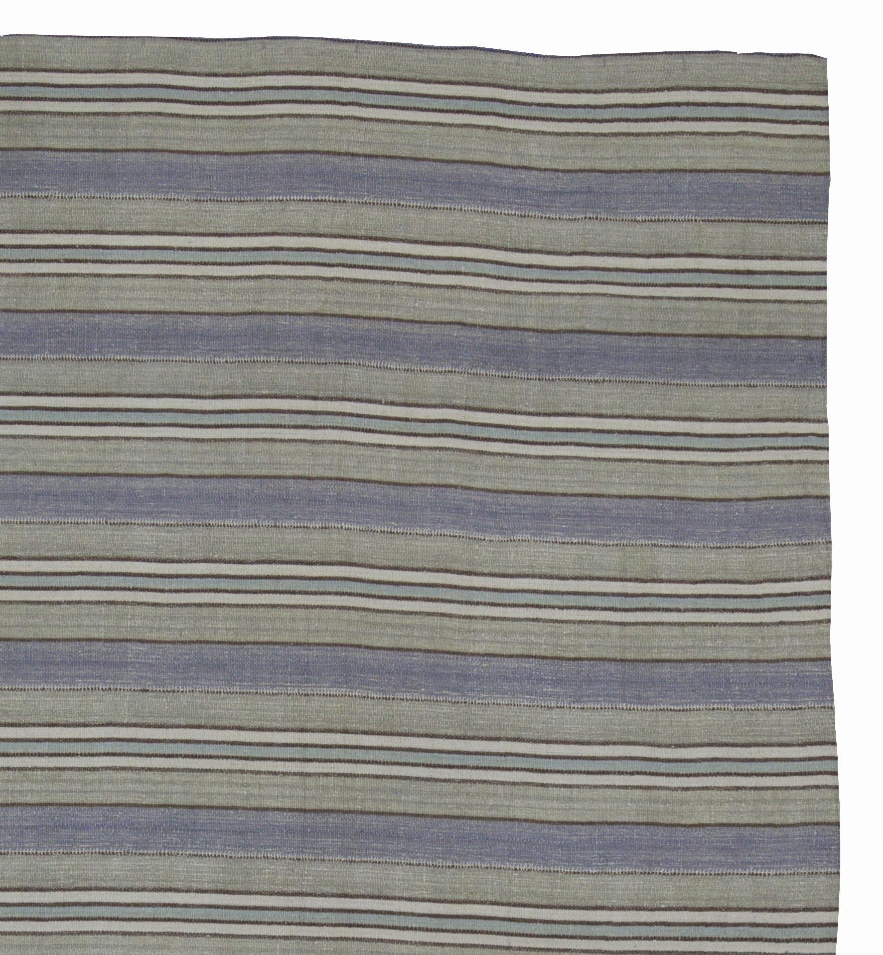 A new production Turkish rug handwoven from the finest sheep’s wool and colored with all-natural vegetable dyes that are safe for humans and pets. It’s a traditional Kilim flat-weave design featuring a lovely blue and gray striped field with black