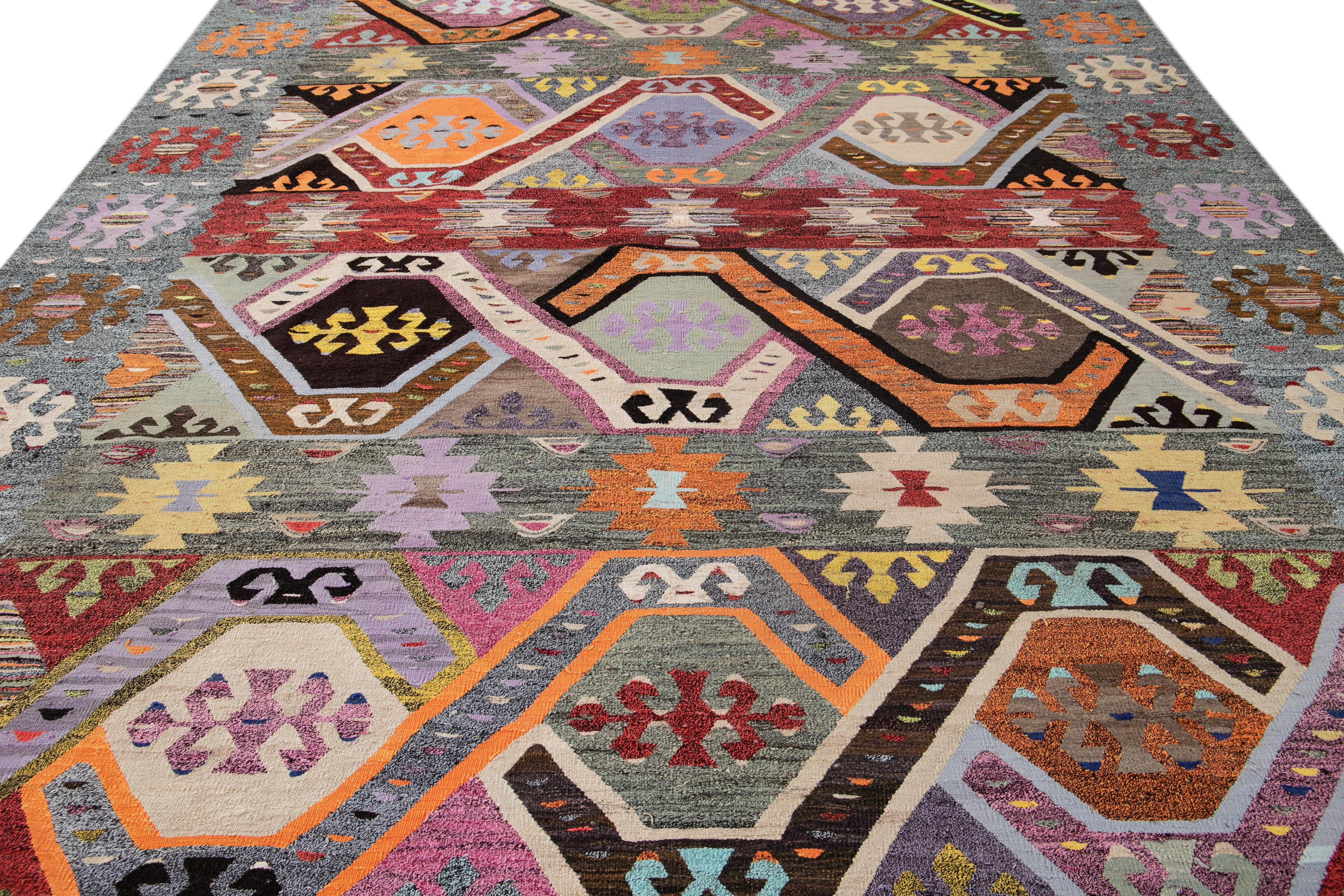 This Indian rug showcases a contemporary Kilim flatweave style crafted from premium wool. Its gray colors complement a captivating geometric pattern that blends harmoniously with multicolor hues.

This rug measures 10' x 13'5