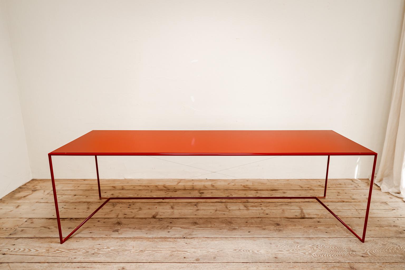 Une table en acier laqué rouge chaud qui peut être utilisée à l'intérieur et à l'extérieur.
 