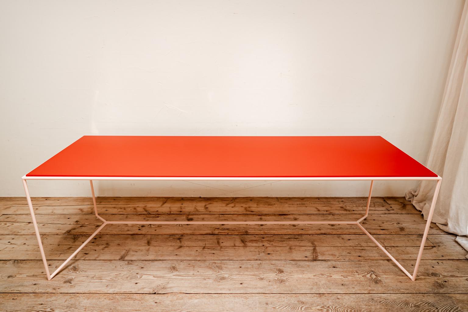 A lacquered steel table with lacquered mdf reversible pink/red table top.
  