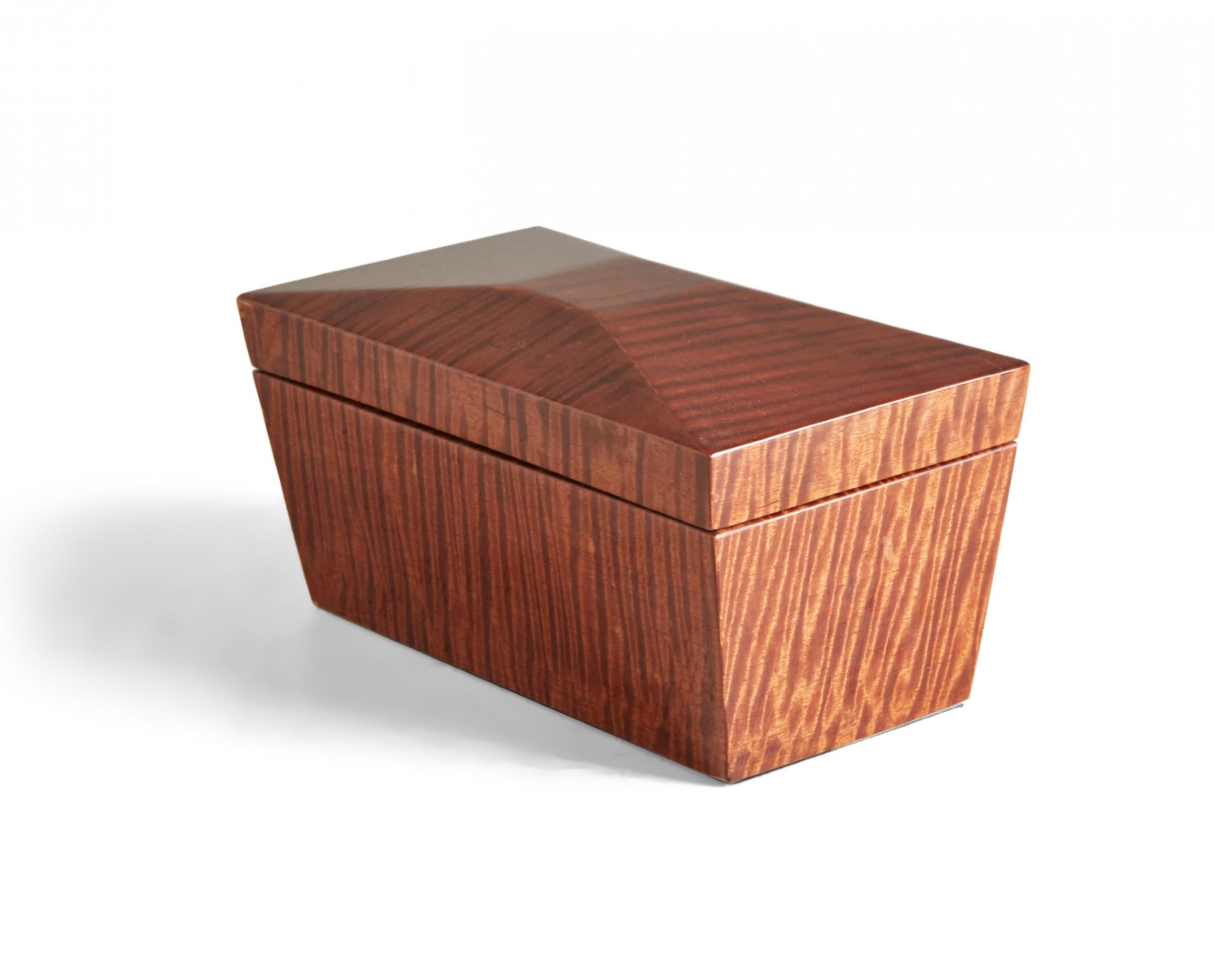 Contemporary decorative lacquered tiger maple box with a rectangular profile with faceted lid and tapered sides, and a brass-hinged lid that opens to reveal two interior compartments covered with black painted wooden square lids with turned knobs.