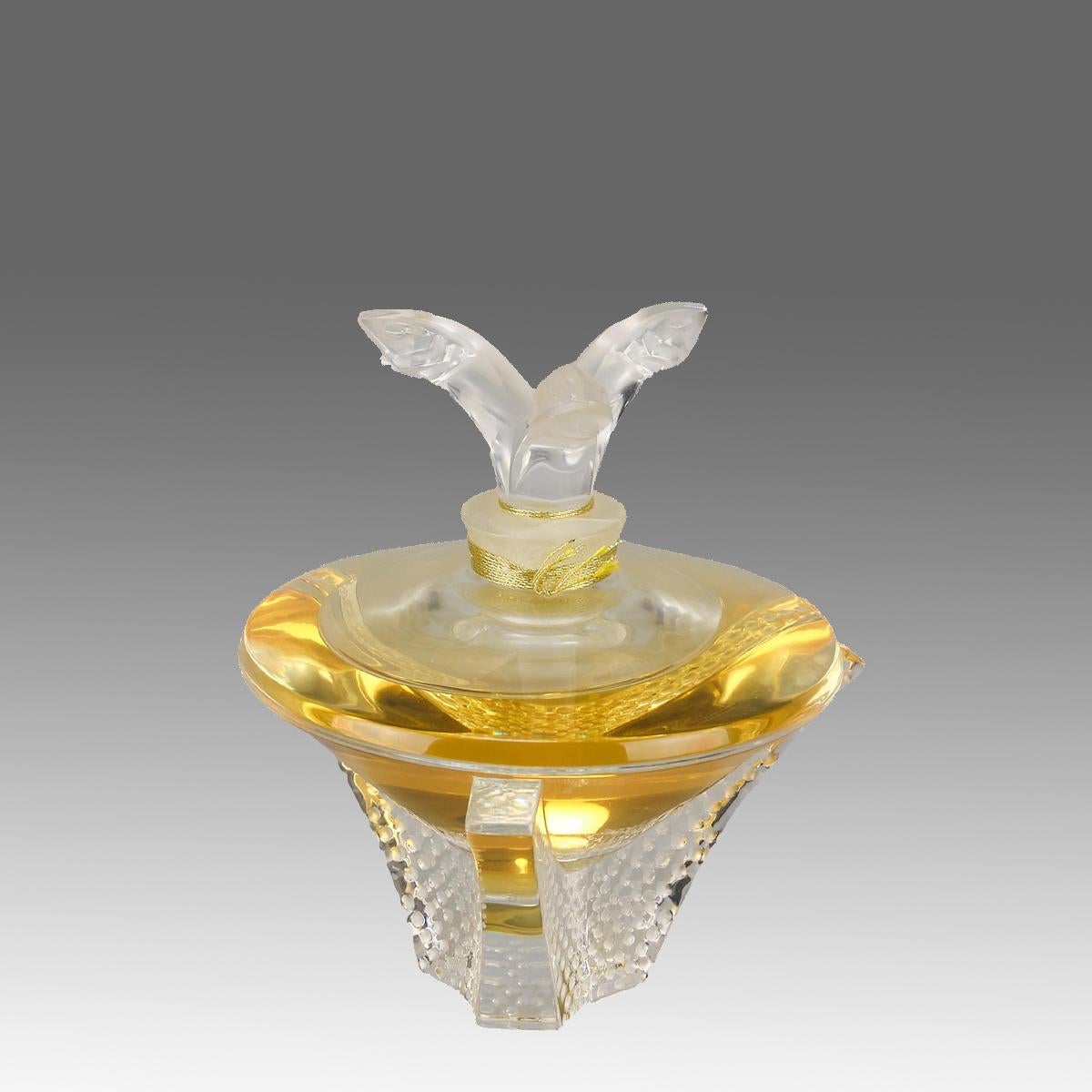 Ein auffälliger Parfümflakon aus Klar- und Milchglas in limitierter Auflage. Der Klarglaskörper enthält das Originalparfüm von Lalique und einen Milchglasstopfen in Form von drei springenden Fischen, die auf einem dreibeinigen Sockel mit feinen