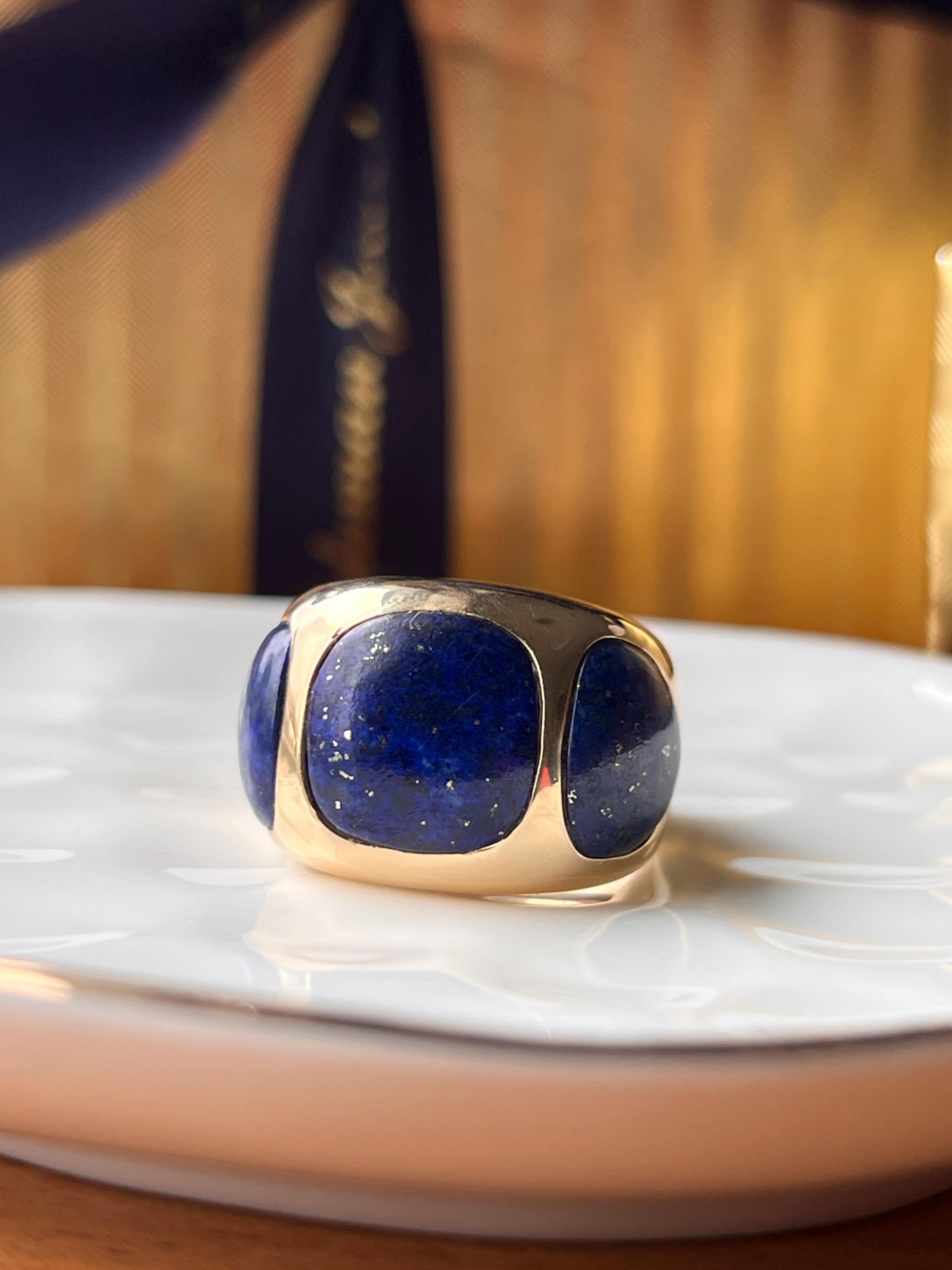 This contemporary 18K yellow gold ring features three striking lapis lazuli inlays, each measuring approximately 10–12mm, radiating a deep celestial blue flecked with natural golden inclusions. The bold, sculptural design tapers gracefully from