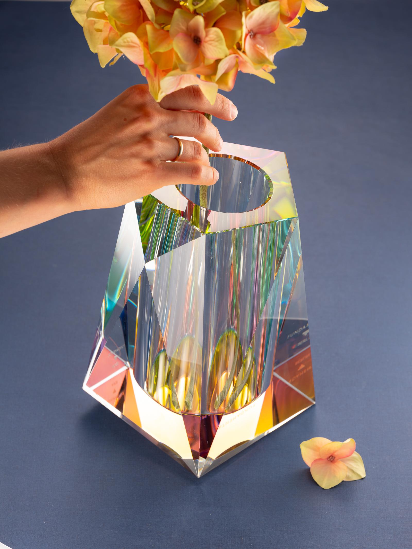Fai una dichiarazione audace con un cristallo futuristico! Tagliato e lucidato a mano da artigiani tradizionali, questo vaso scultoreo e angolare utilizza una pellicola dicroica per esagerare l'effetto di divisione dei colori del cristallo, portando