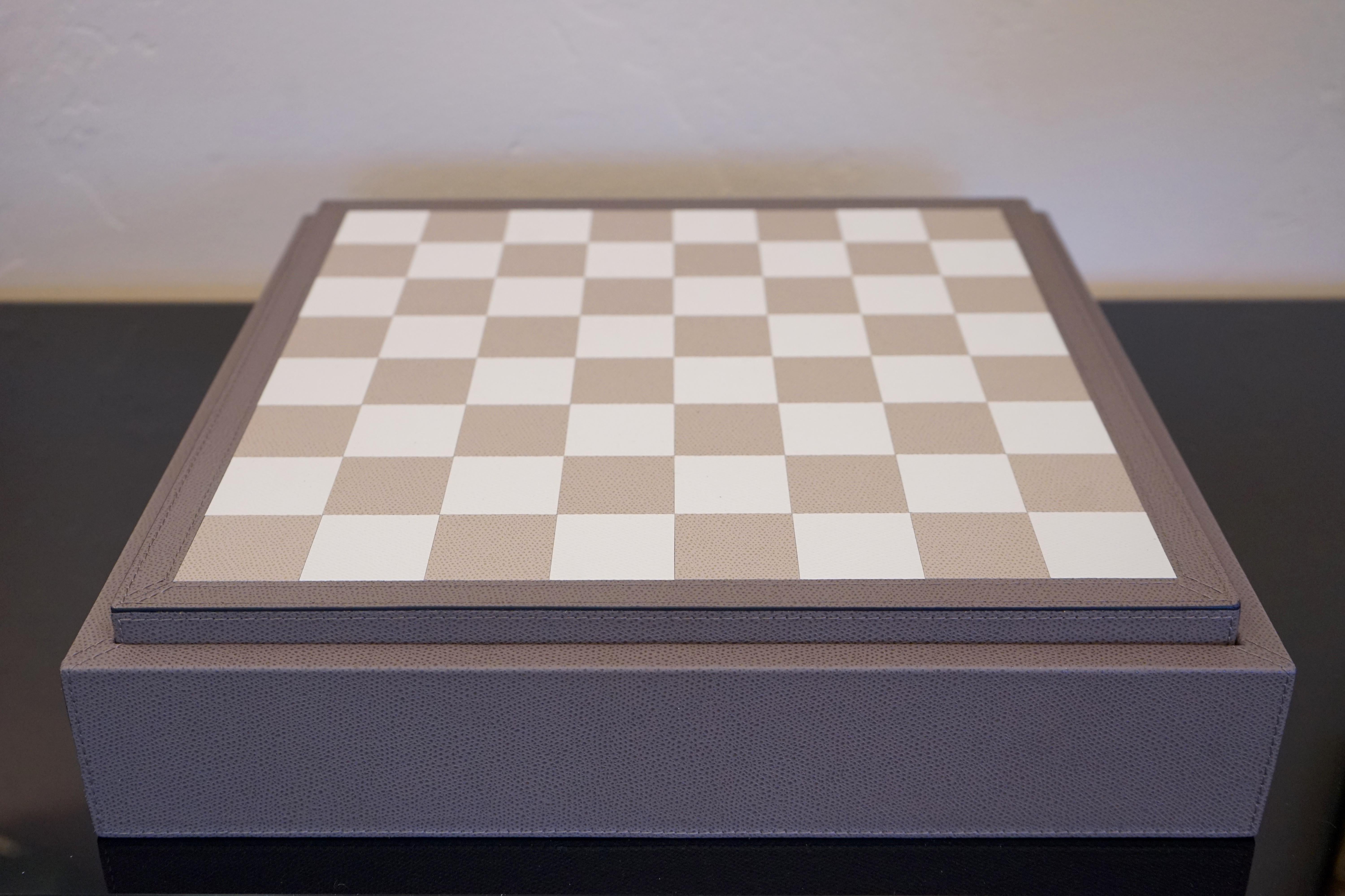 Contemporary leather board game with a removable lid to hide game pieces for three games: chess, dominos, and checkers. A perfect accessory for any desk or table. Stone and ivory leather color.
