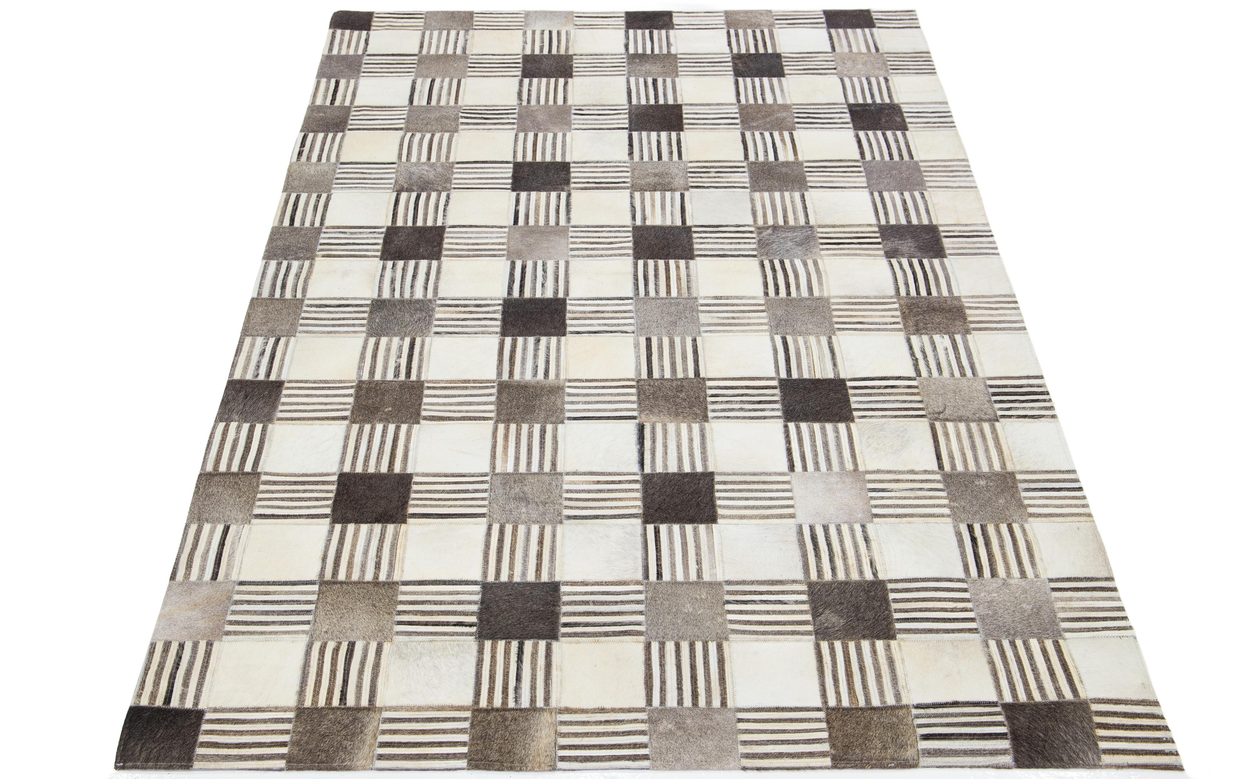 Ein zeitgenössischer Teppich aus Leder und Wolle mit einem geometrischen Flickendesign mit beigen, grauen und braunen Akzenten, hergestellt aus 100% natürlichem MATERIAL. Dieser Teppich ist handgeschnitten und sorgfältig genäht, um dieses schöne
