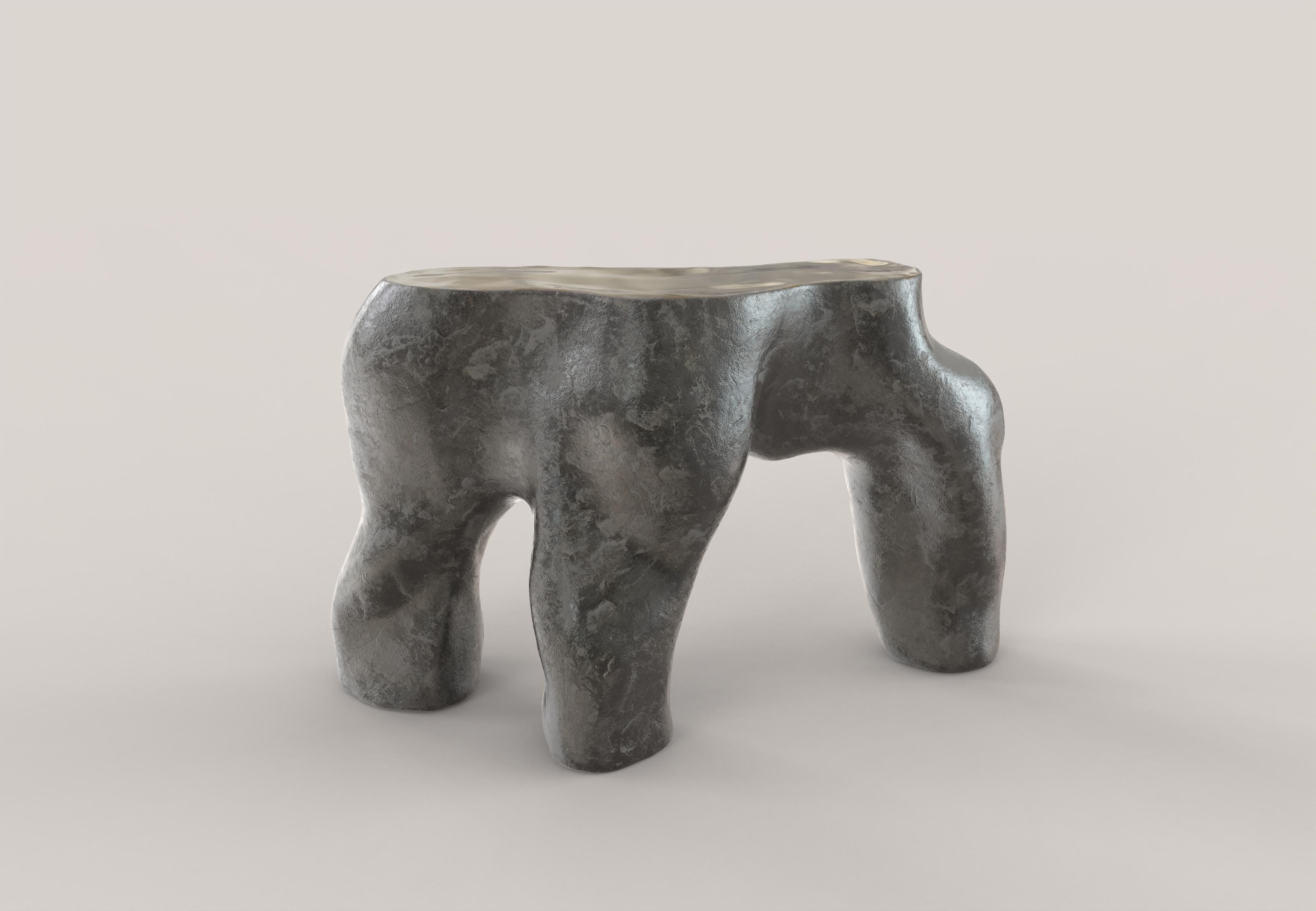 A sculptural console made of patinated and polished cast bronze. The shapes of the table and the patina on the body of the piece recall natural architecture, constructions born of an organic matter in motion, growing. The clean-cut and
