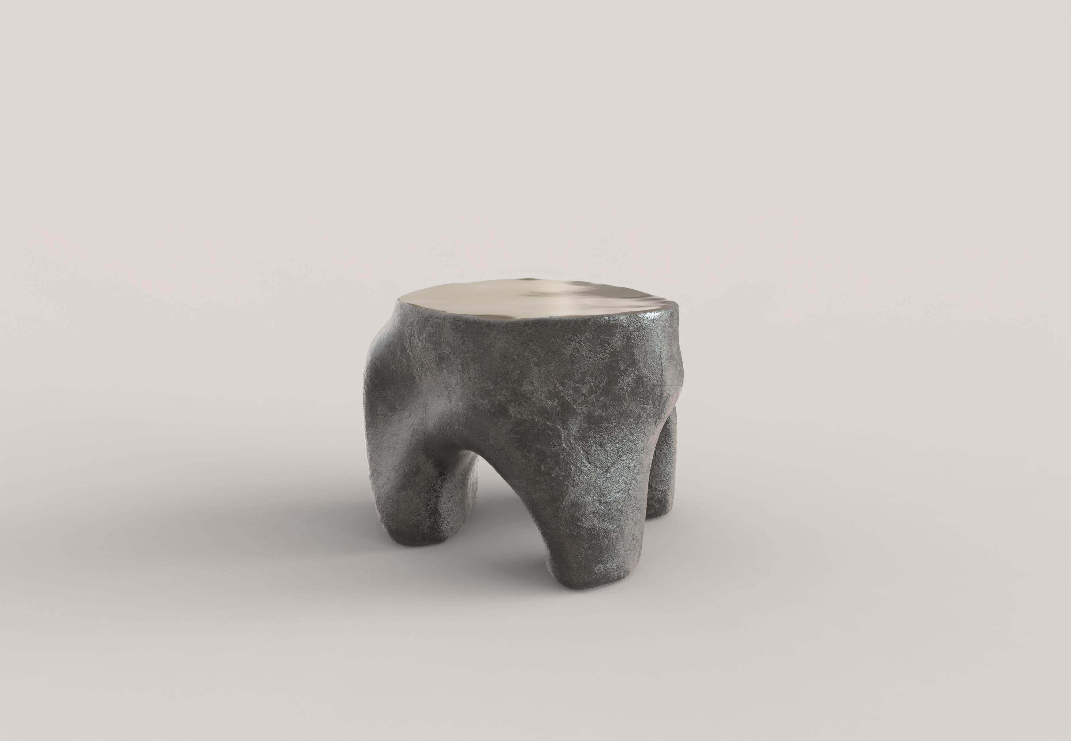 A sculptural low table made of patinated and polished cast bronze. The shapes of the table and the patina on the body of the piece recall natural architecture, constructions born of an organic matter in motion, growing. The clean-cut and
