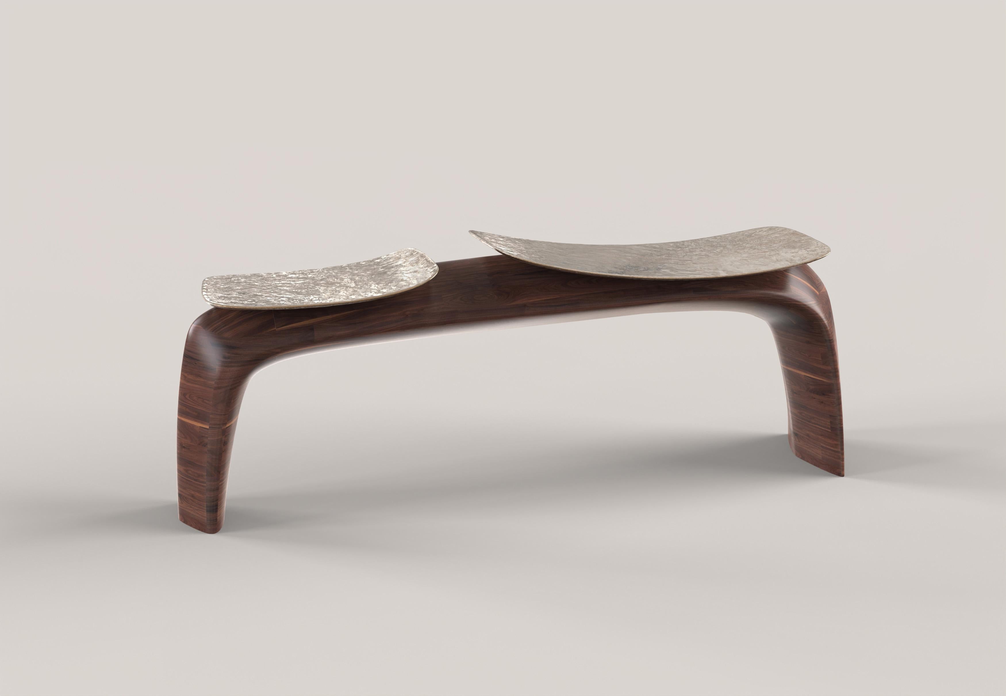 Ce banc du 21e siècle est conçu en travaillant avec une approche sculpturale sur deux matériaux : le bois massif et le bronze coulé. Le bois est sculpté, créant un arc de lignes à la fois douces et fermes qui constituent la structure de l'objet. Les