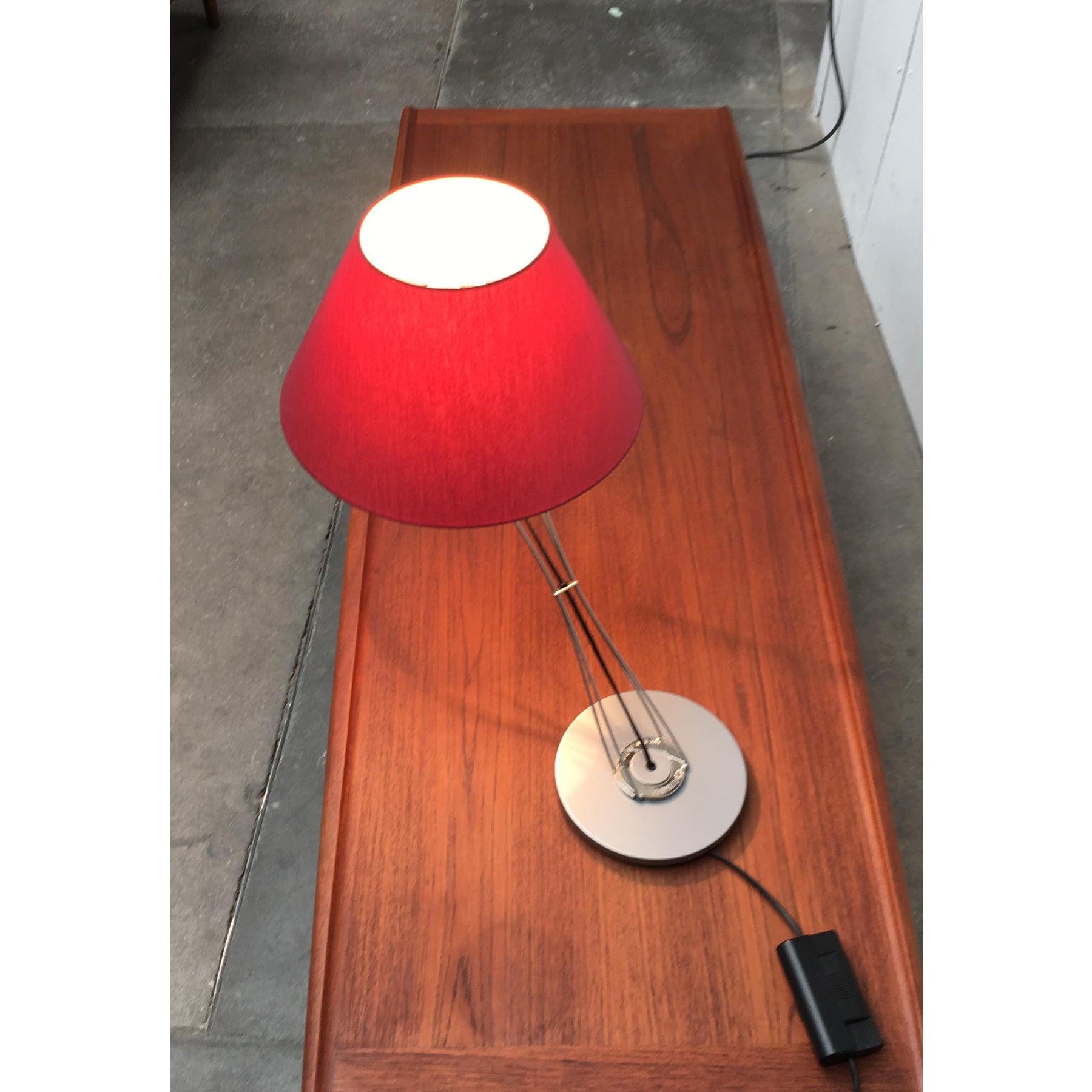 Liz table lamp by Lumina designed by Yaacov Kaufmann.

Technical design language combined with classic table lamp aesthetics.
The shade in a strong red tone has a classic shape, the lamp arm consists of a flexible and filigree lattice structure.