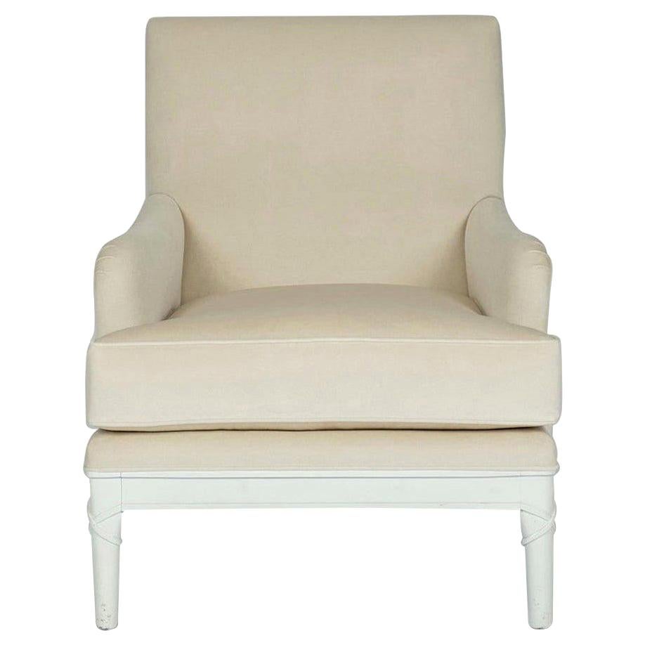 A vintage white painted lounge chair with contemporary carved ribbon at legs. This lovely solid wood mahogany carved frame is eight way hand tied and newly upholstered in a creamy ecru low pile velvet with a new feather down wrapped spring coil seat