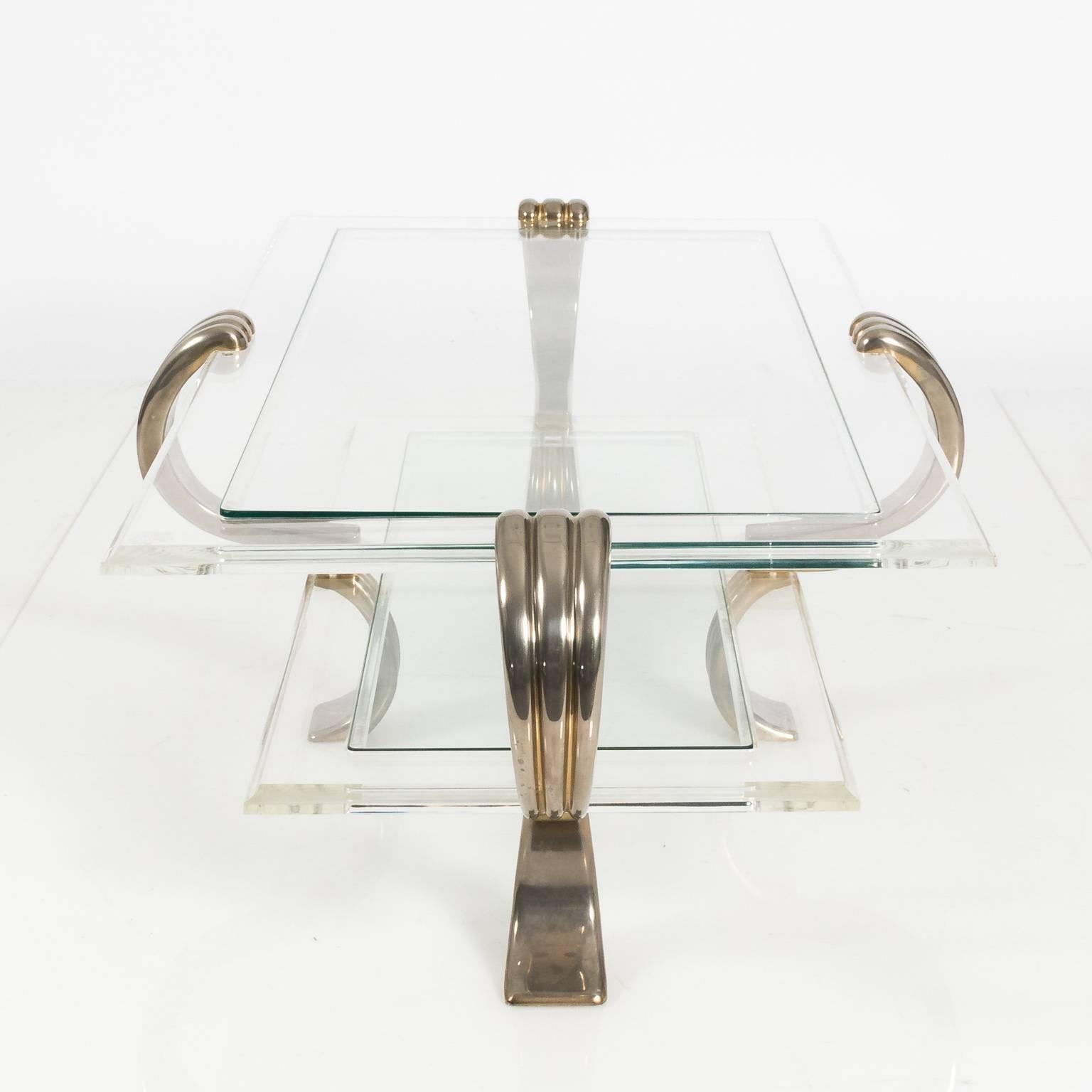 Contemporary Lucite coffee table with chrome-plated, brass mounted bracket legs with a lower shelf.