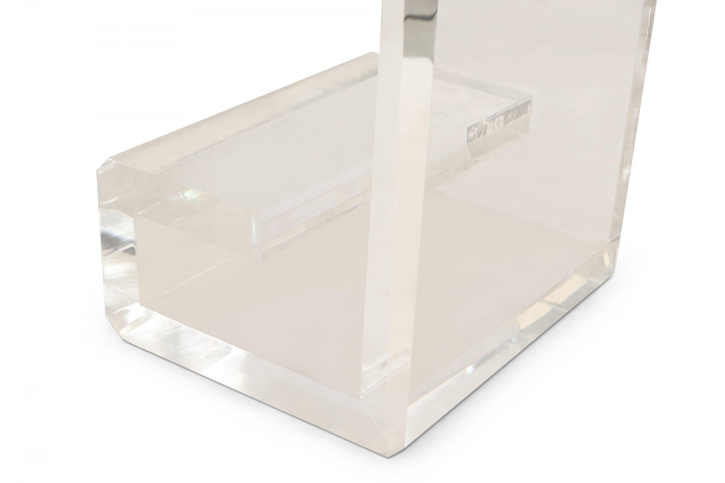 Escritorio contemporáneo de lucita con 3 cuadrados de espejo envejecido incrustados en la superficie superior, un compartimento/estante de cristal poco profundo y patas geométricas en forma de volutas (diseñado por Geoffrey Bradfield).
 