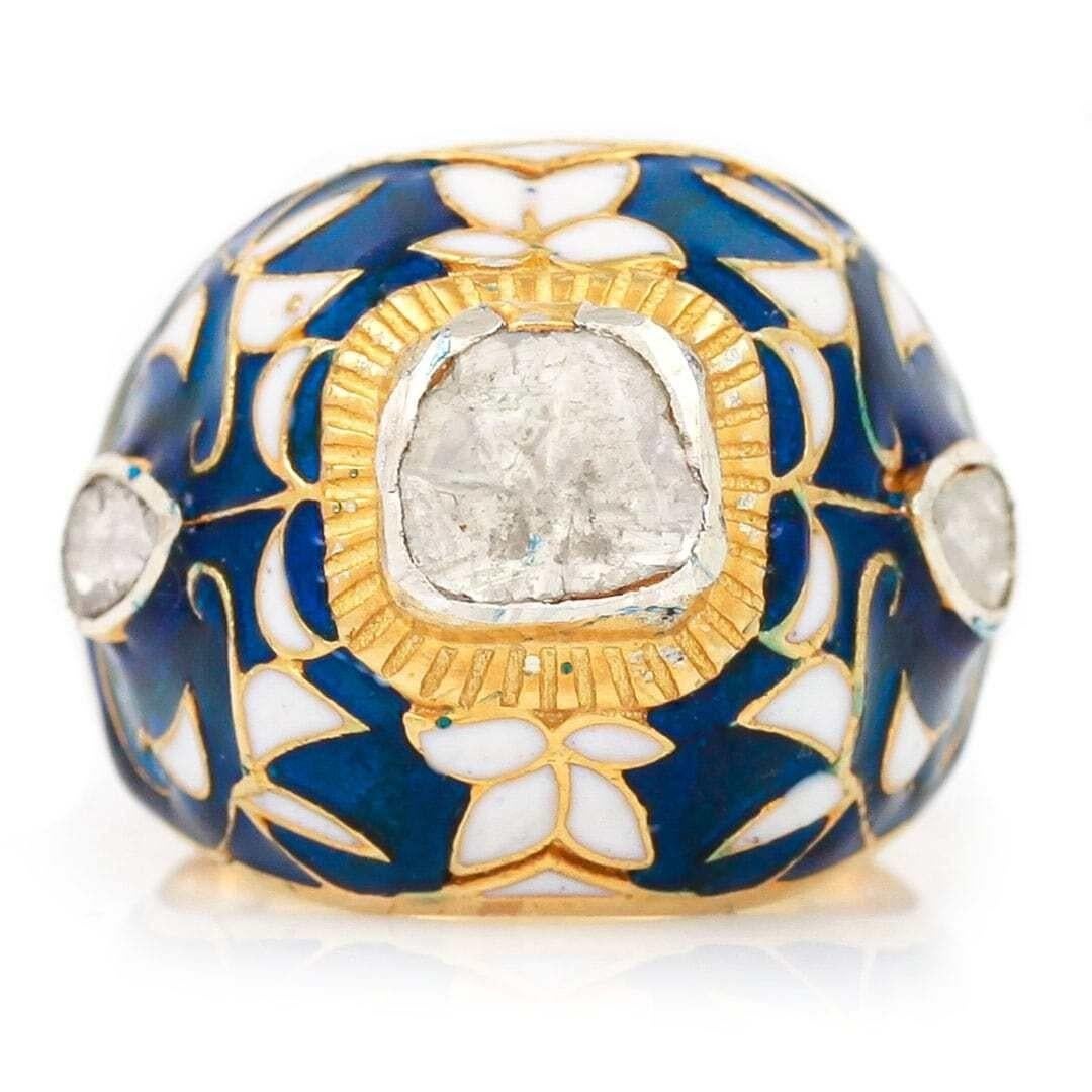 An impressive statement Mughal style ‘Polki’ rose cut diamond and vari-hue enamel bombe ring. The ring which is centrally set with a large rose cut diamond is surrounded by an ornately carved foliate designs that are inlaid with blue and white