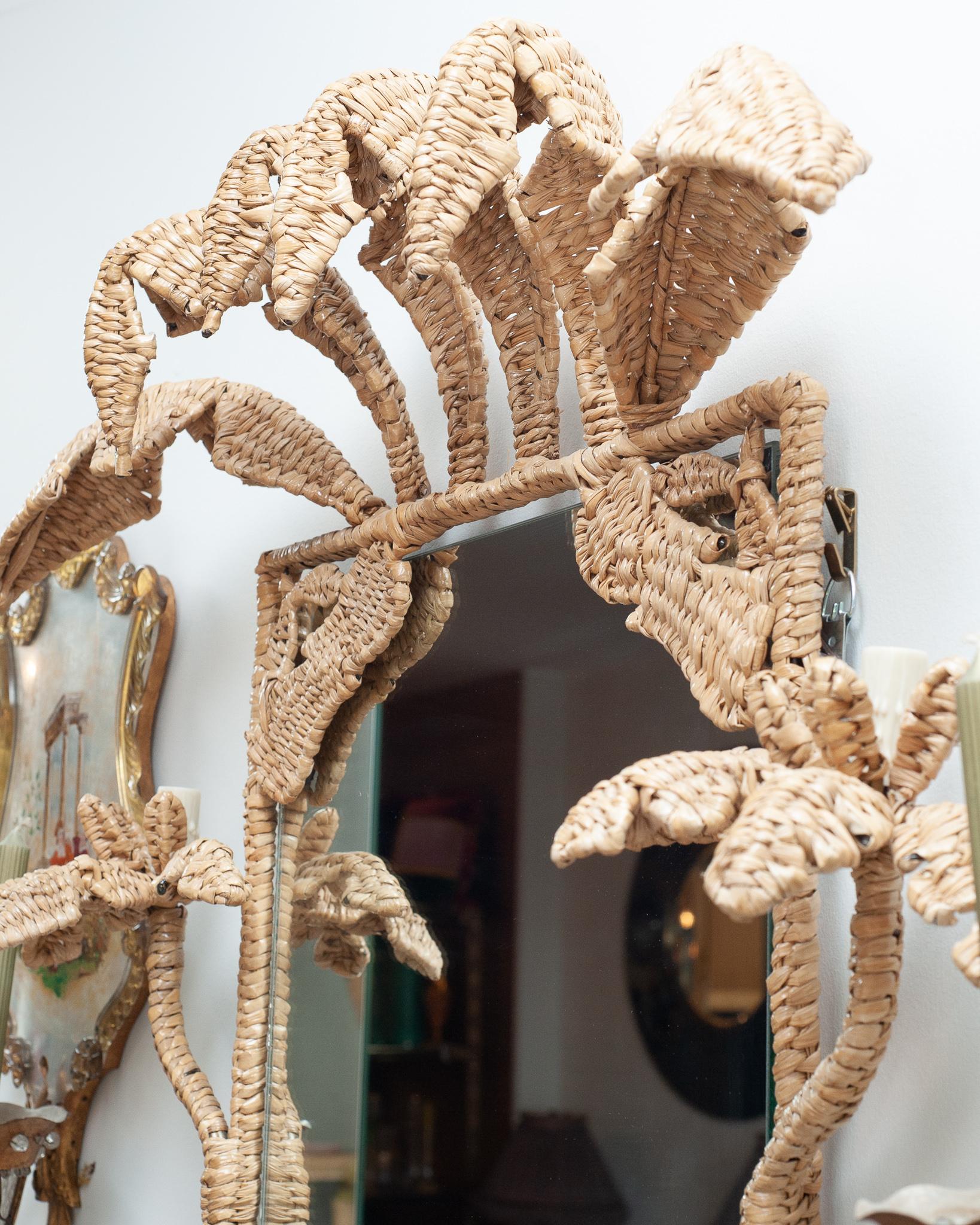 A stunning Mario Lopez Torres illuminated palm tree mirror, constructed with a metal frame and expertly woven natural rattan. This mirror features candlelights which can be electrified into the wall. Labeled with a brass medallion by Mario Lopez