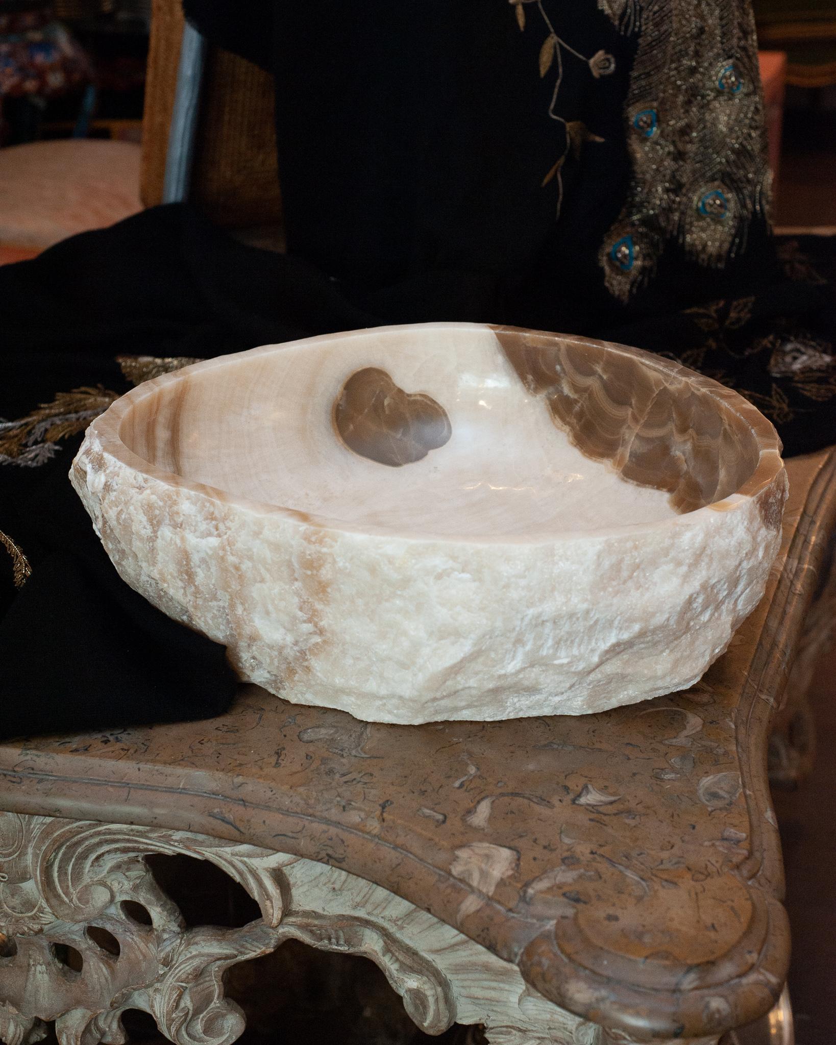 Invitez l'énergie curative de l'onyx dans votre maison avec un bol minéral massif exceptionnel. Ce bol en pierre à bord brut est strié de blanc et de beige, avec un intérieur très poli.