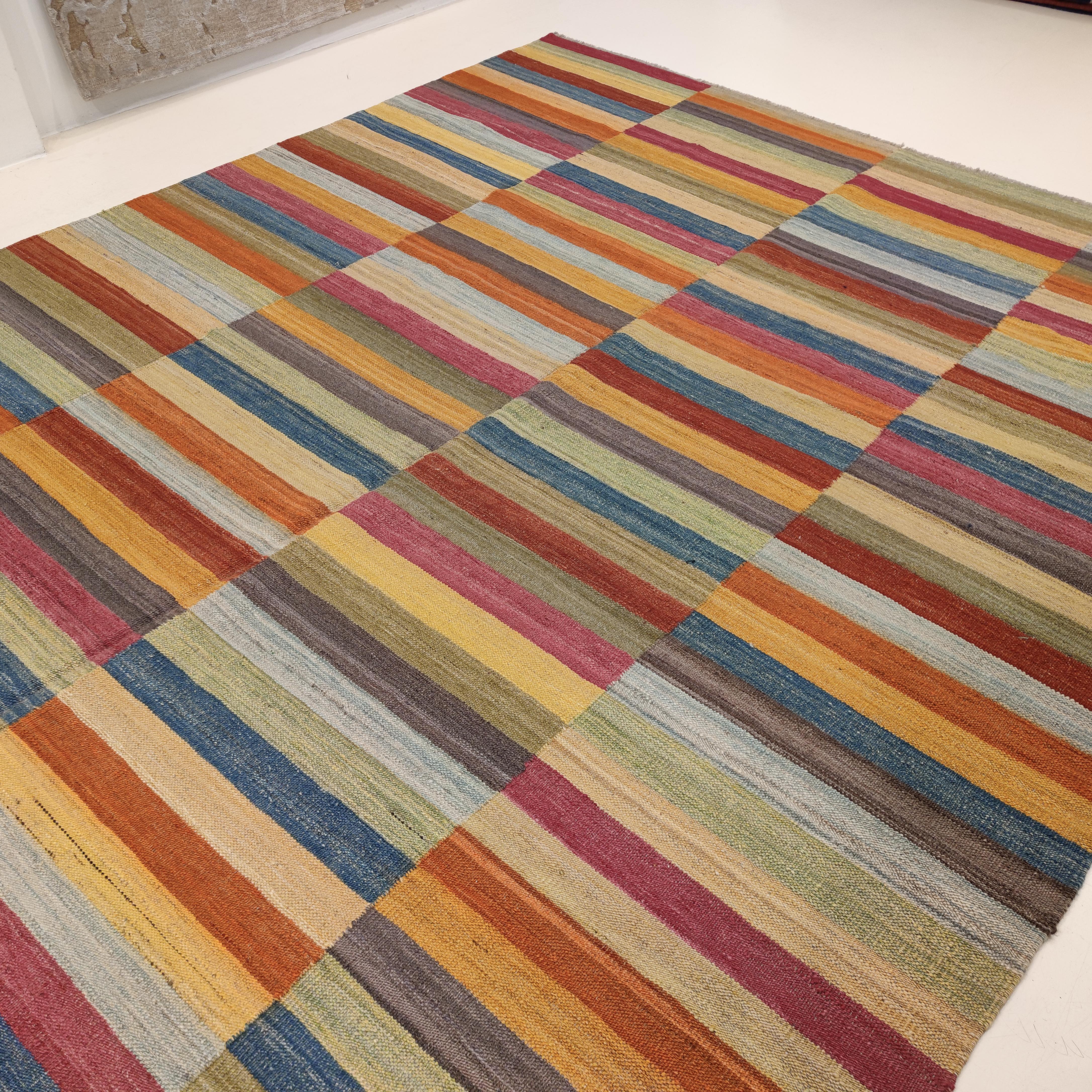 A stunning contemporary kilim, hand-woven with fine quality Afghan hand-spun wool dyed in a range of predominantly organic dyes. The palette is arranged in a vertical repeat of horizontal stripes, woven as if it was composed of four distinct panels.