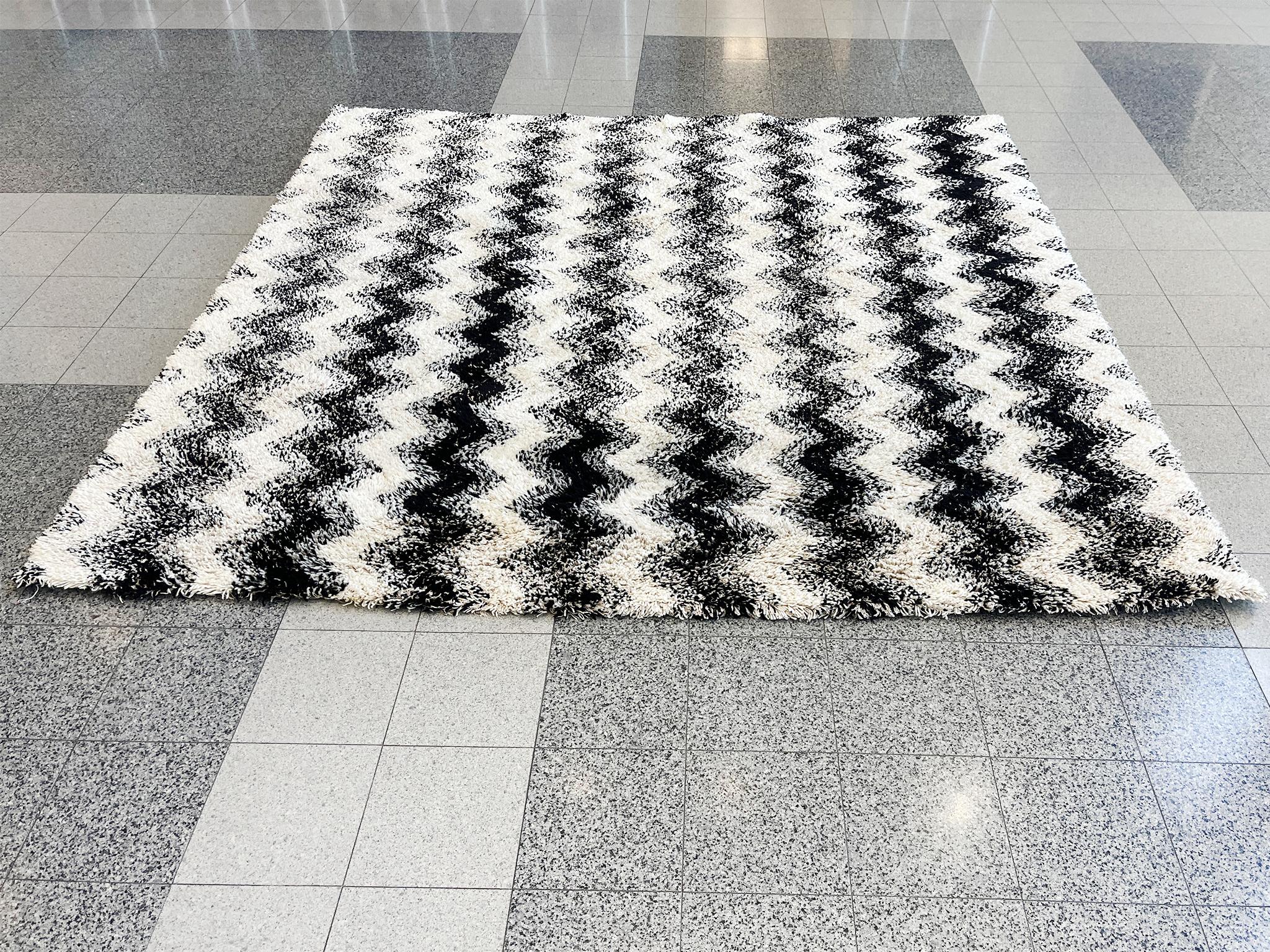 Dieser moderne handgewebte Teppich ist eine Kreation des Textilstudios Merida. Es ist eine üppige Wolle in Schwarz und Weiß, gewebt in einem Zickzackmuster, das die Oberfläche belebt. 

Abmessungen:
9'3