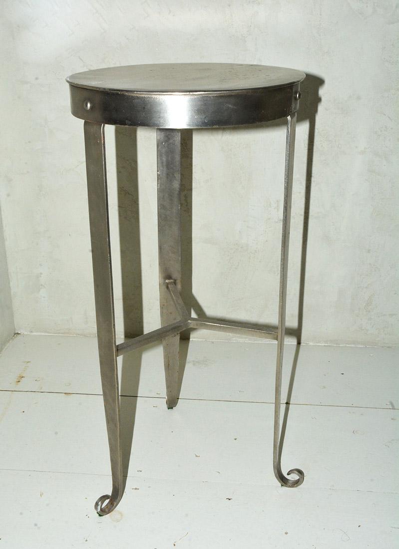 The contemporary nickel-plated steel counter, bar stool or plant stand has three tapered legs with soldered stretchers and ending with cunningly curled feet. The round top has an apron with the legs bolted to it. 2 available, sold
