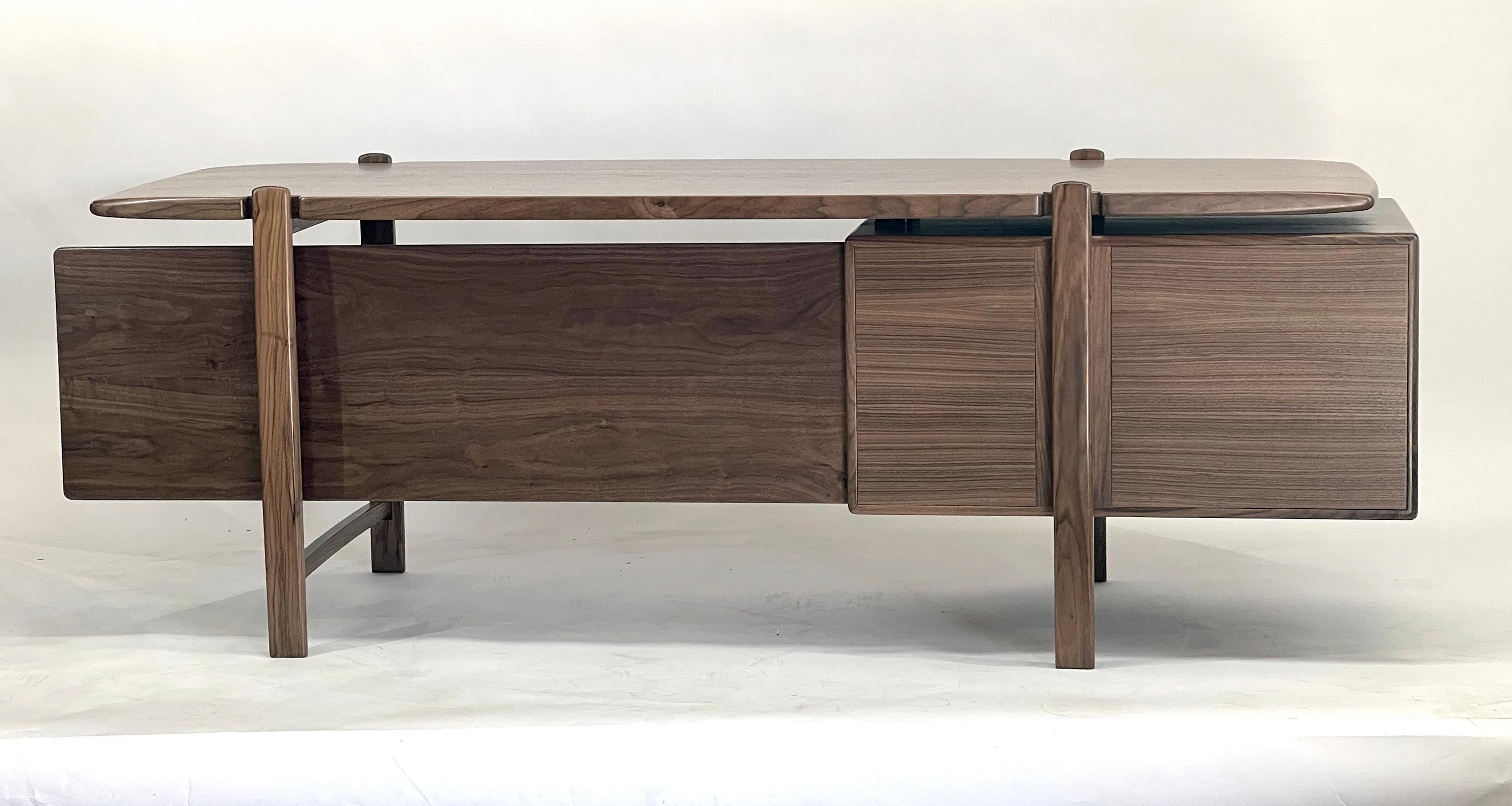 Présentation de ce remarquable  Bureau d'inspiration mid-century en bois massif. Ce bureau dégage une impression de beauté et de masculinité, tout en étant pratique grâce à ses quatre tiroirs spacieux et à son élégant panneau de courtoisie.