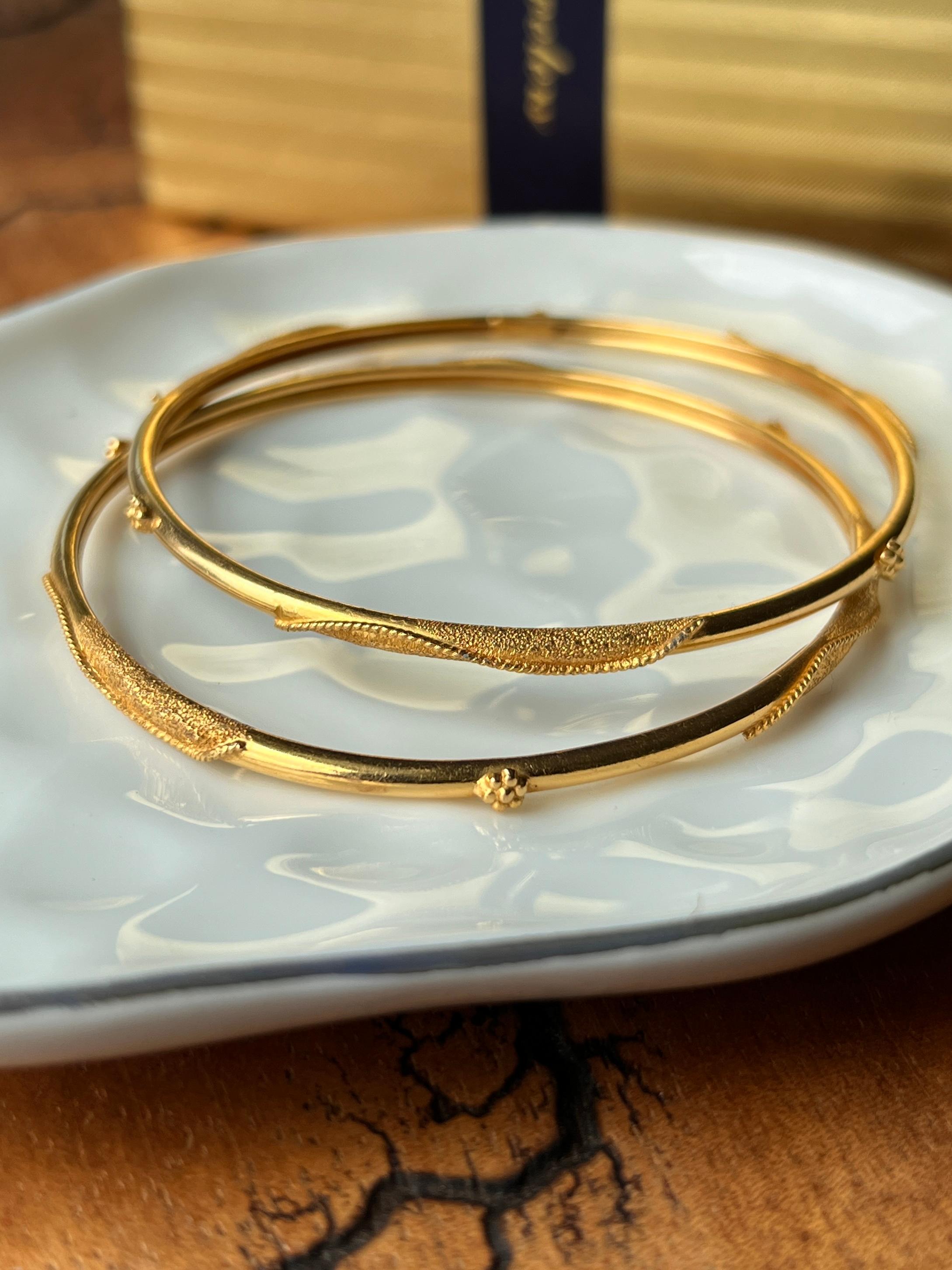 Ein Satz Armreifen aus 18-22 Karat Gelbgold aus dem Nahen Osten, die mit Eleganz und Tradition gefertigt wurden. Die Armreifen zeichnen sich durch eine Kombination aus polierten und strukturierten Golddetails aus, die mit kleinen Blumenmotiven aus
