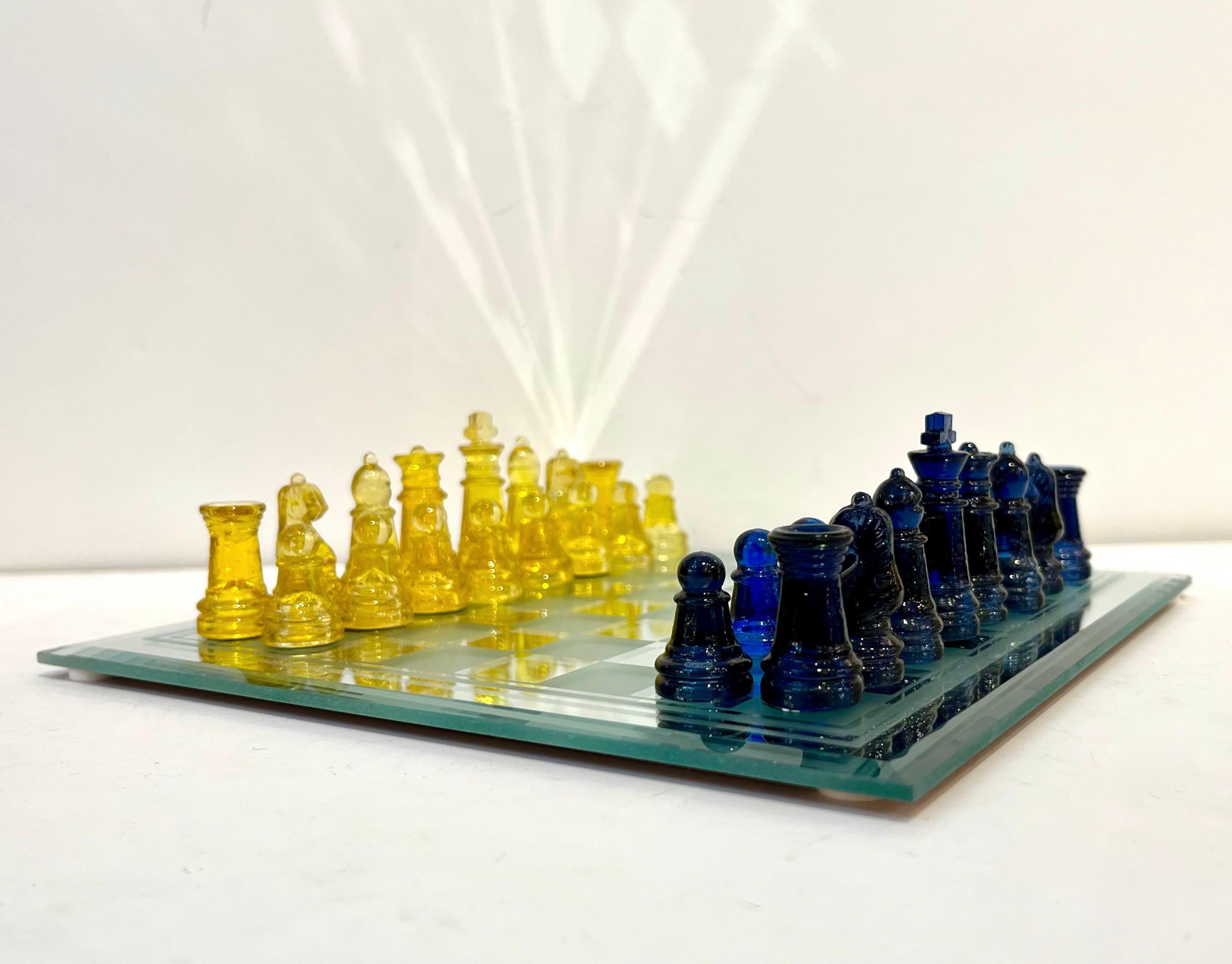 A fun Italian portable chess game of modern organic design, the detailed chess pieces are molded in night blue and yellow Murano Art glass, the mirror glass chessboard is decorated with frosted and mirrored squares, edged with a quality beveled