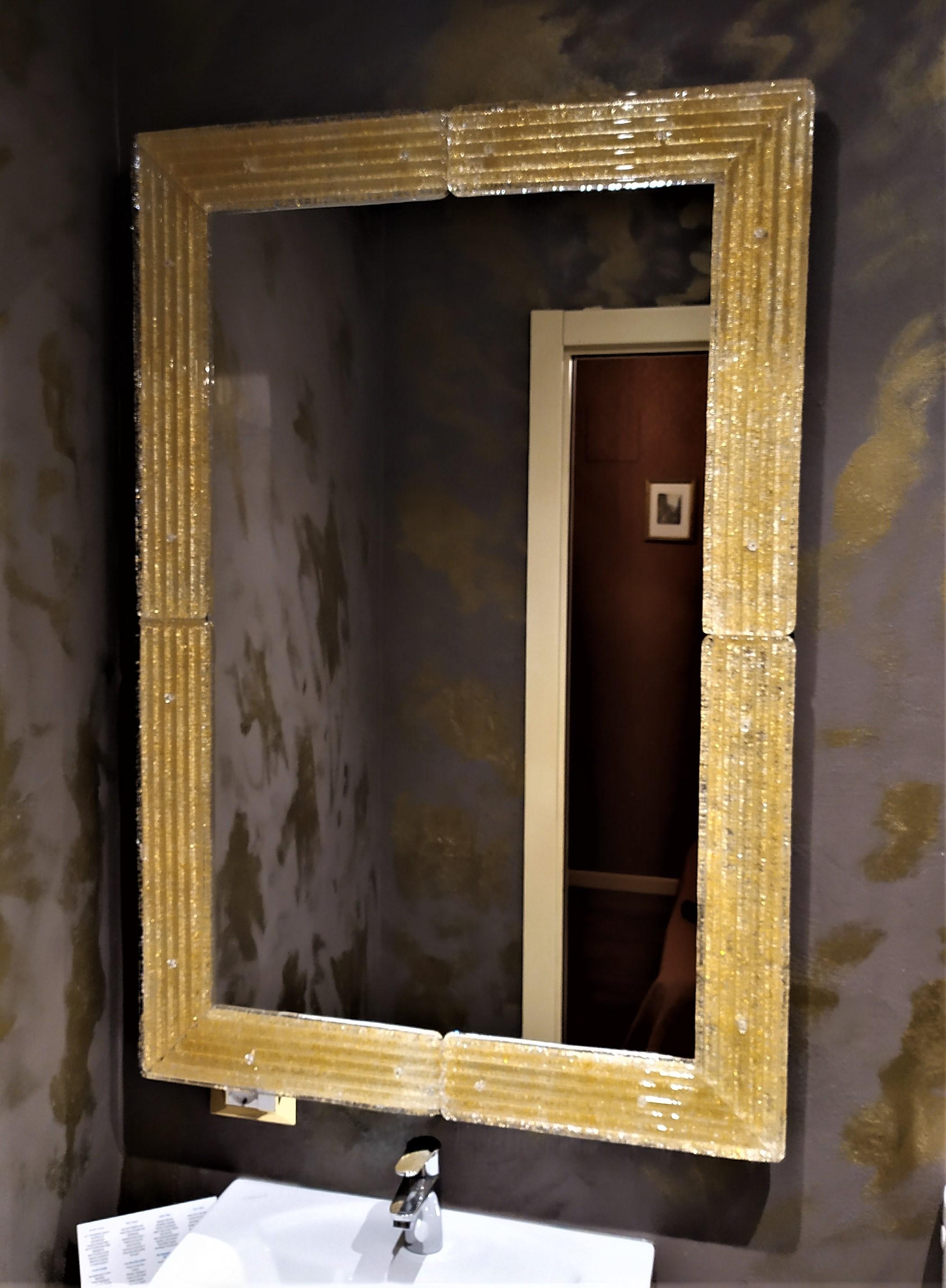 Contemporary style mirror of the 21st century, with the luxurious murano glass frame produced according to the ancient Muranese traditions and processes, frame wich is then cut, shaped and polished in the corners, drilled and fixed to the structure