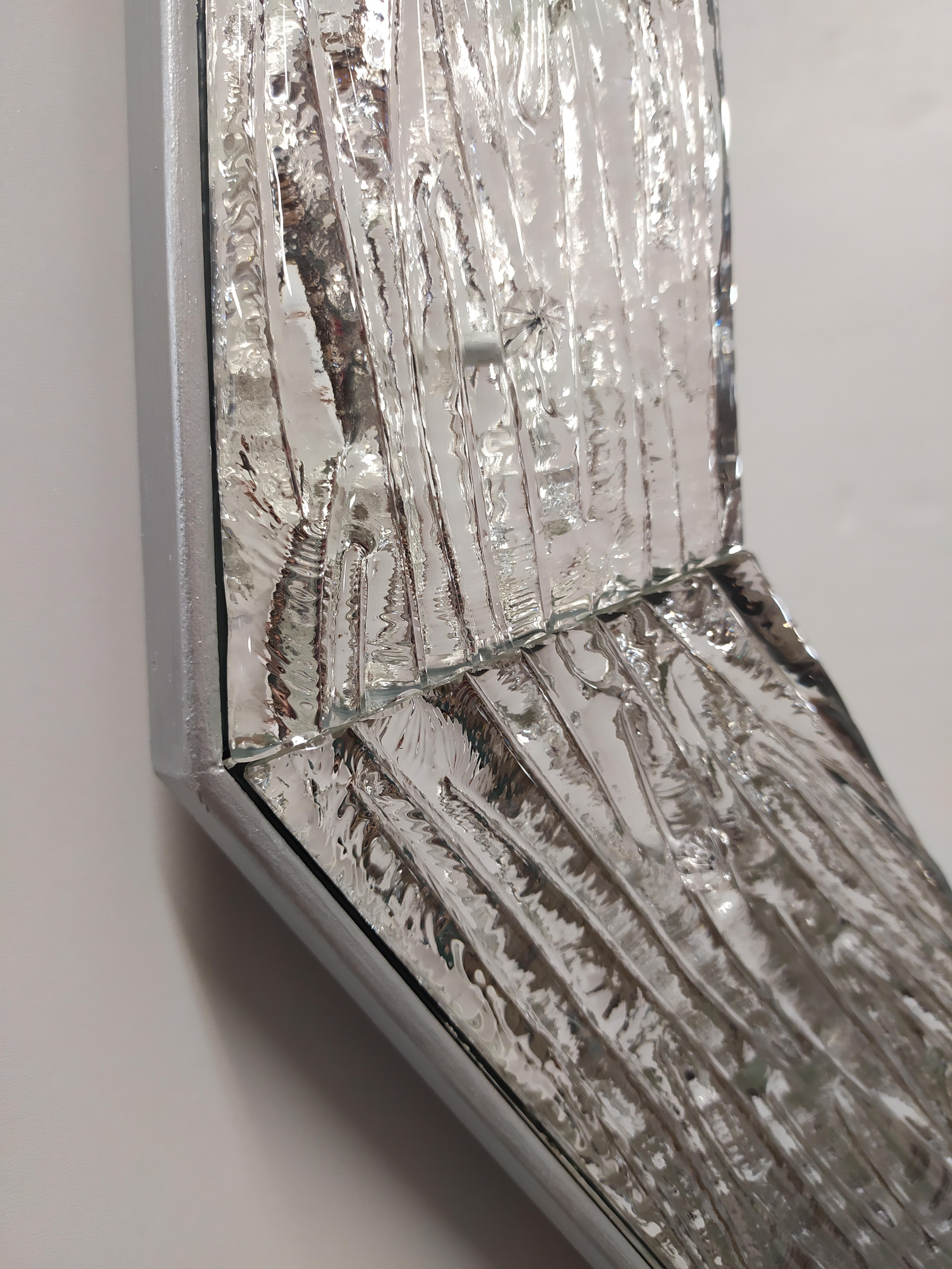 Zeitgenössischer Spiegel im Stil des 21. Jahrhunderts, mit einem Rahmen aus Muranoglas, der nach den alten Traditionen und Verfahren von Murano hergestellt wird. Der Rahmen wird geschliffen, geformt und in den Ecken poliert und dann mit reinem