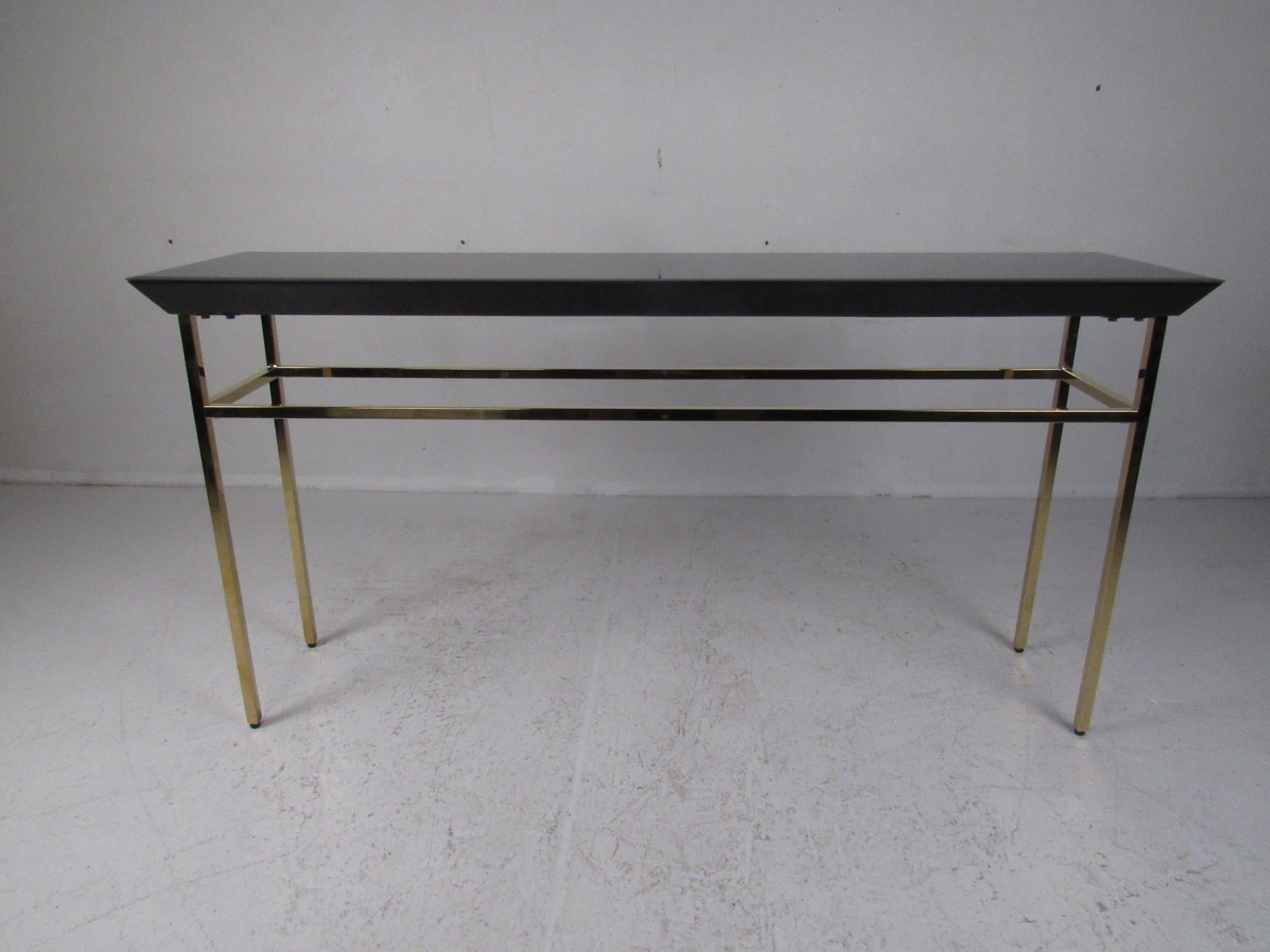 This stunning midcentury style hall table features a black glass top with beveled edges. A sturdy metal base with stretchers supports the rectangular tabletop. This stylish piece looks great in any entryway, hallway, and even behind the sofa. Please