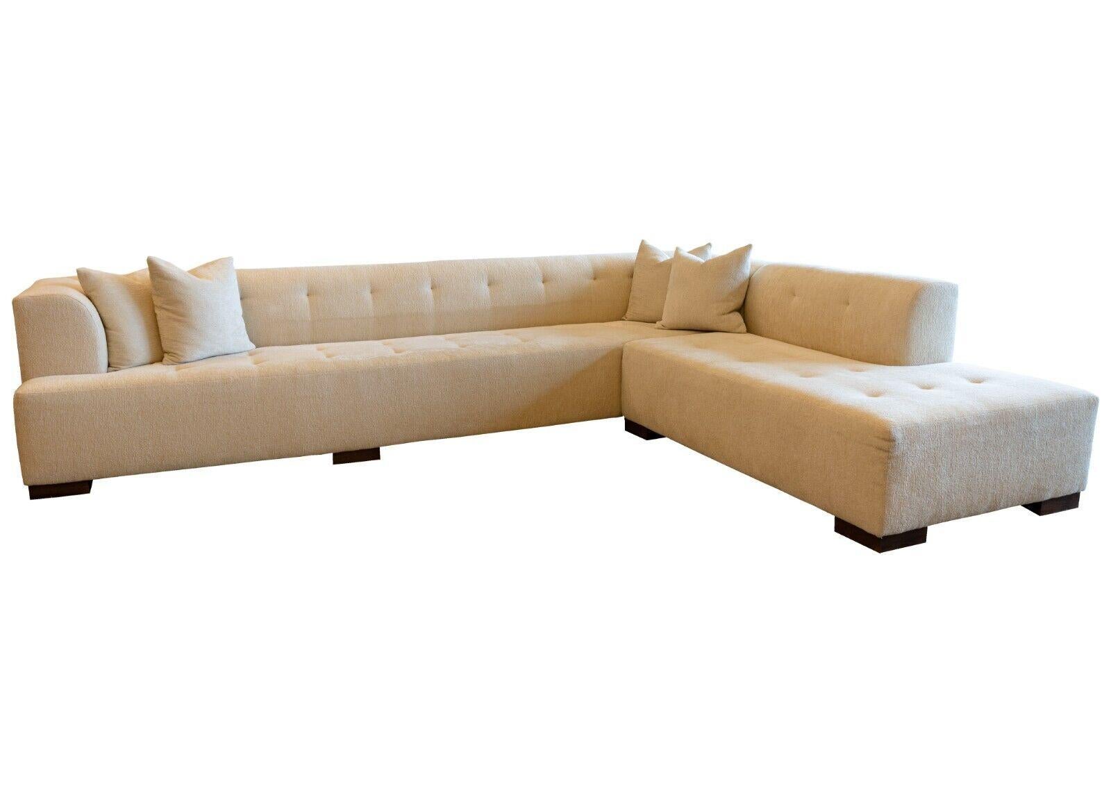 A contemporary modern custom made cream cream tufted glant 2 piece sectional sofa. This gorgeous sectional sofa features a modular 2 piece design, in a very elegant cream color upholstery. This piece is constructed with large square, wooden legs