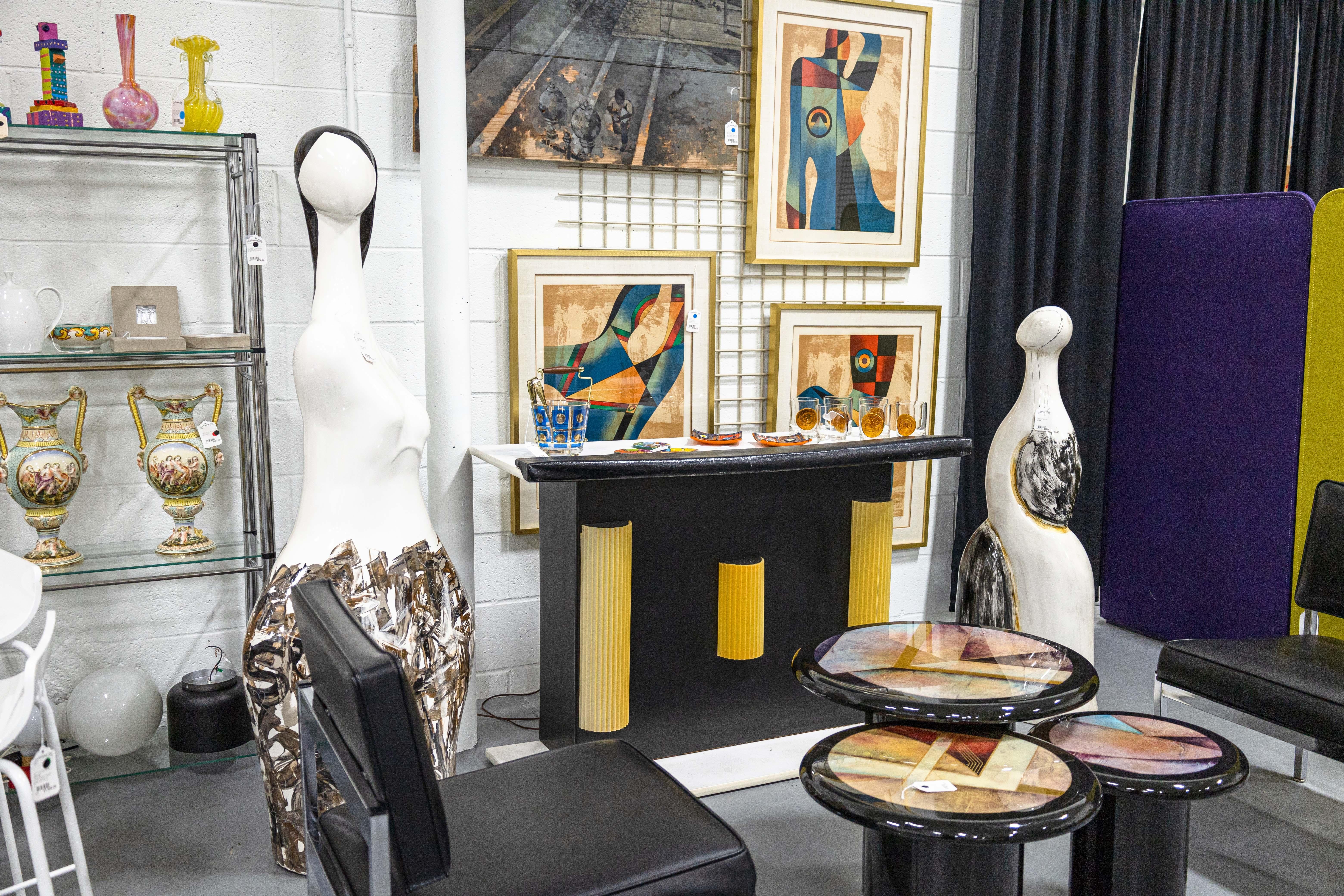 A contemporary modern figurative female figure floor sculpture. This stunning decorative piece features an exaggerated female figure with black hair, and a hand painted base. This piece is in very good condition. It measures 61.5 inches tall, 25