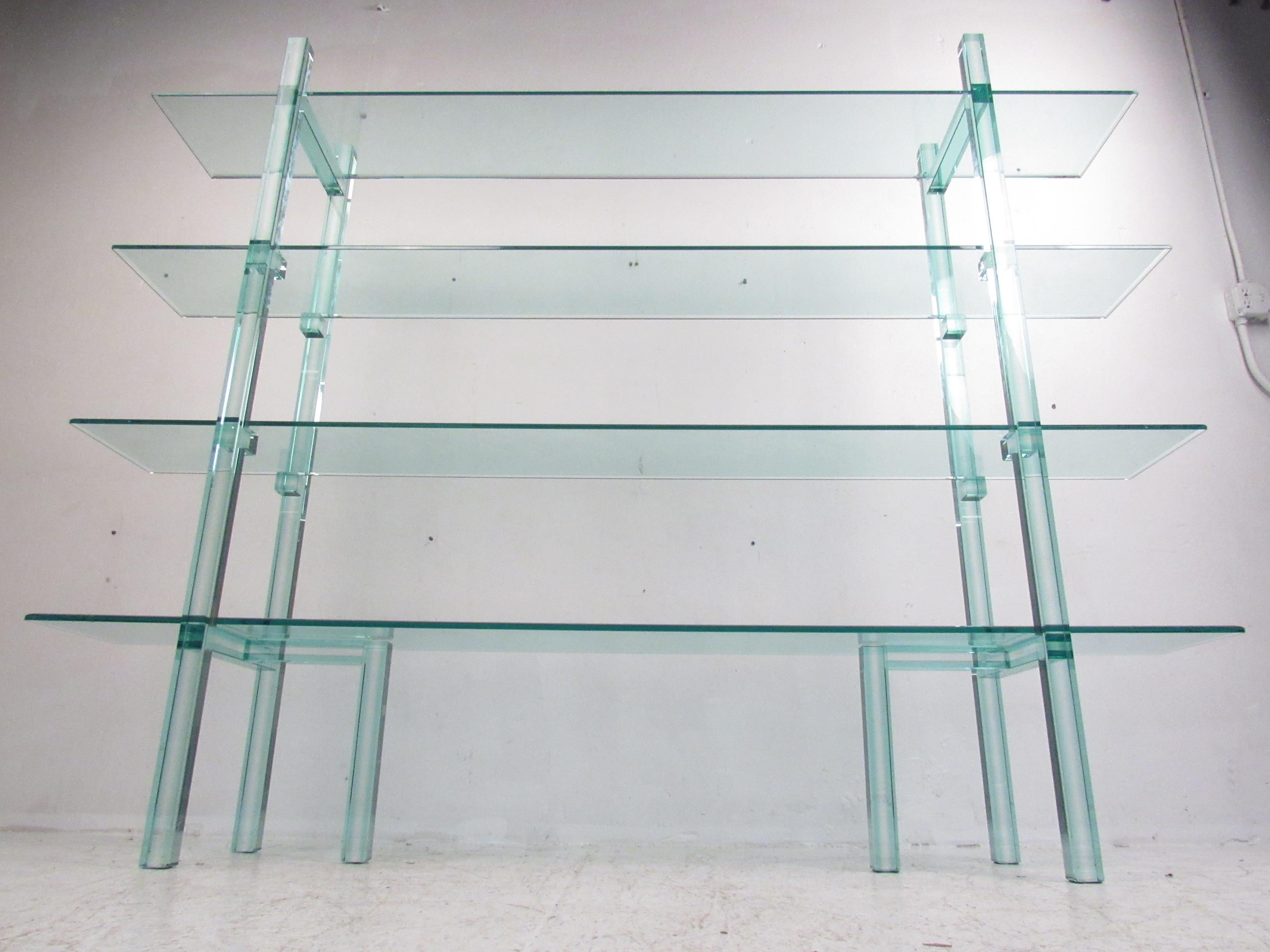 This stunning contemporary modern bookcase is made entirely of glass boasting an impressive blue-green tint through the thick beveled glass. Sleek and unusual design with two tripod base side supports that hold up all four, 86 inch wide glass