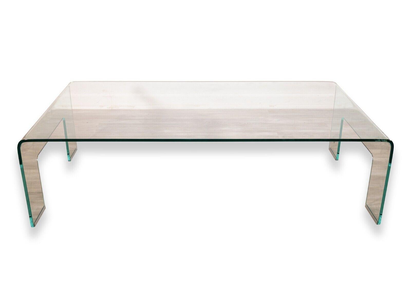 A contemporary modern Italian Calligaris rectangular glass waterfall coffee table. A stunning small coffee table from Italian furniture designer Calligaris featuring an all glass waterfall design, with metal leg covers, and a Calligaris tagging on