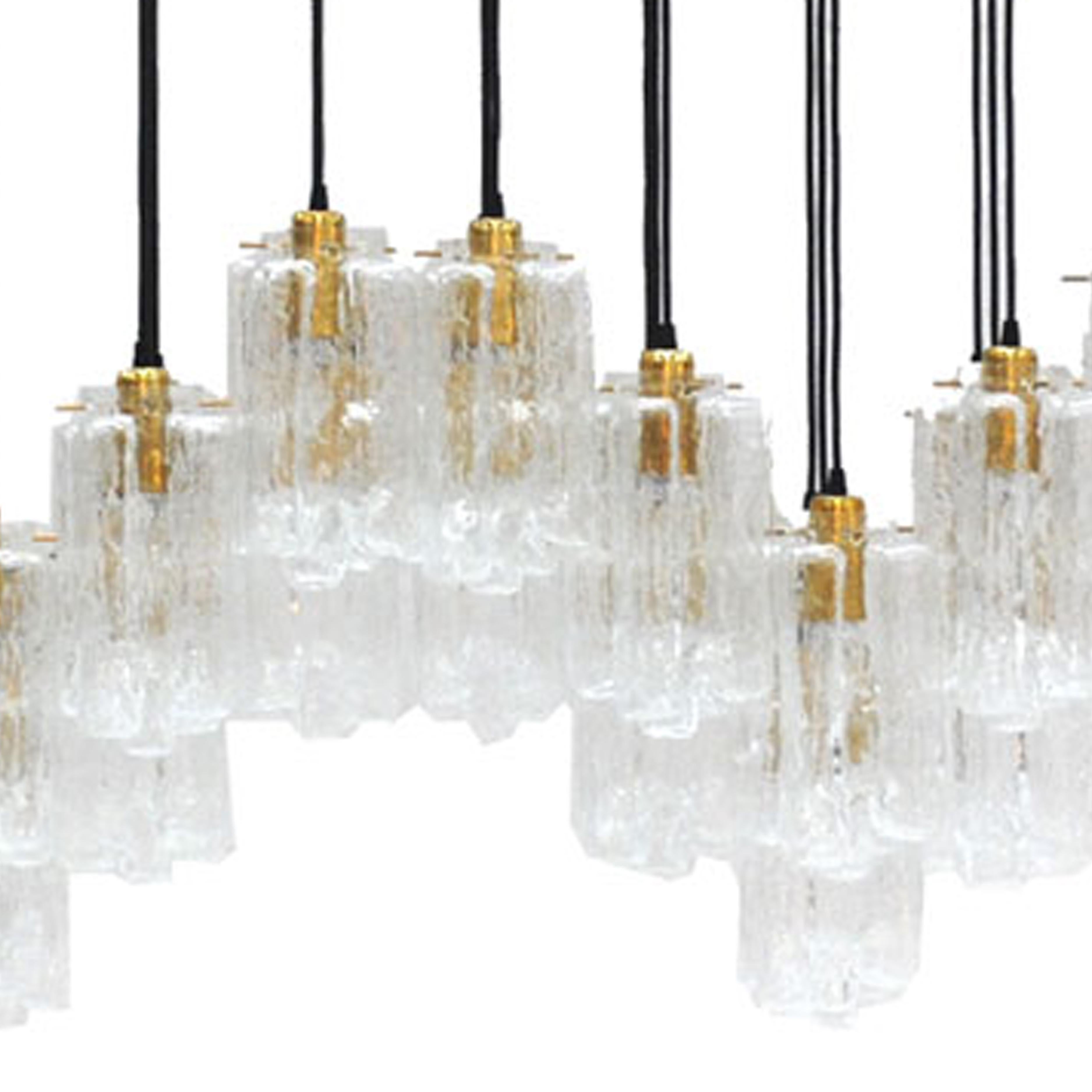 Lámpara de suspensión italiana contemporánea con base rectangular de latón y seis bombillas suspendidas con cristal de Murano tallado a mano y detalles de latón. Fabricada en Italia, esta lámpara combina el diseño moderno con la artesanía