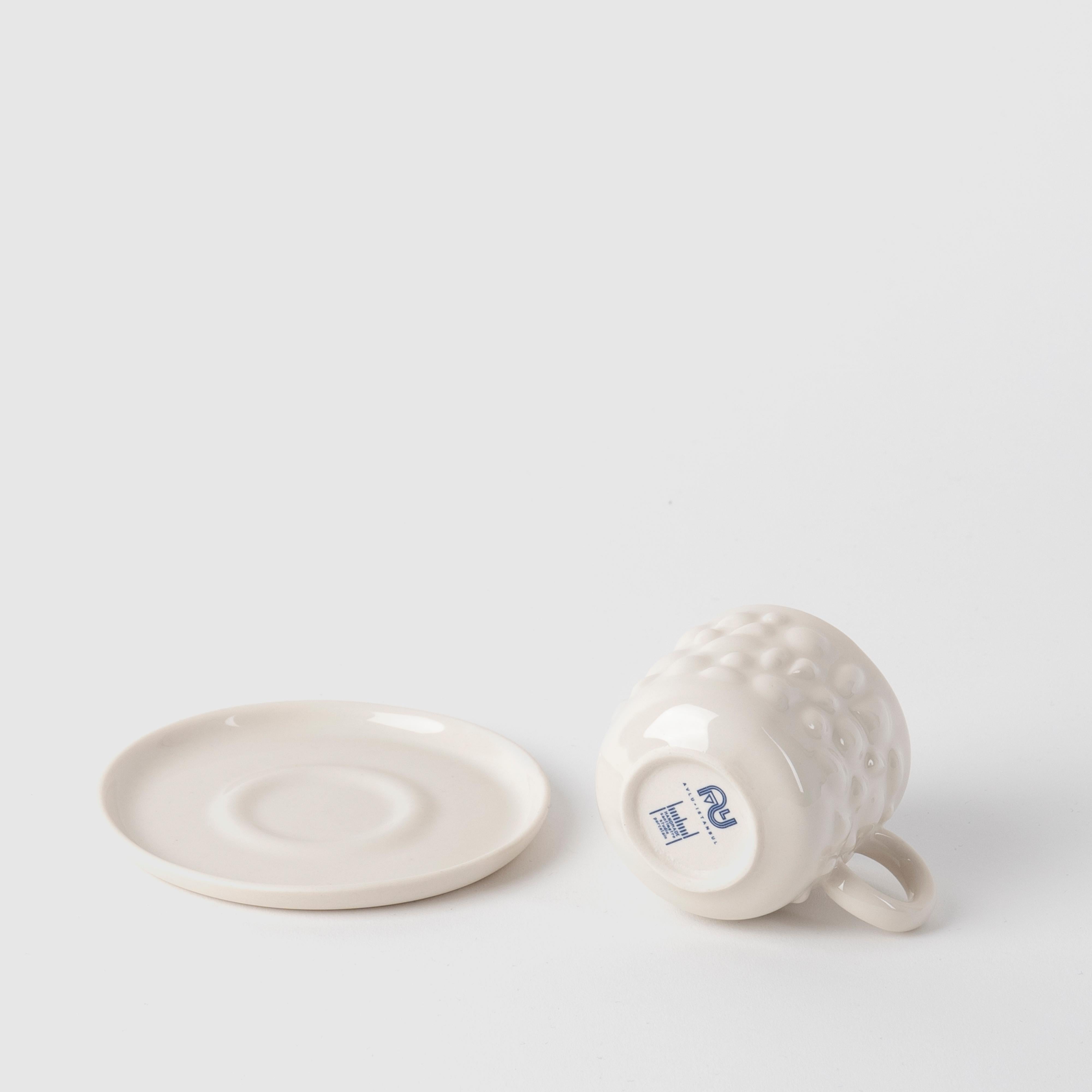 Die Porzellanstücke von Justine sind von den antiken byzantinischen Schmuckstücken inspiriert. Zartes Porzellan verwandelt Tassen in zeitlose Designobjekte, indem es die Perlen- und Steindetails von Schmuckstücken in fließende Formen