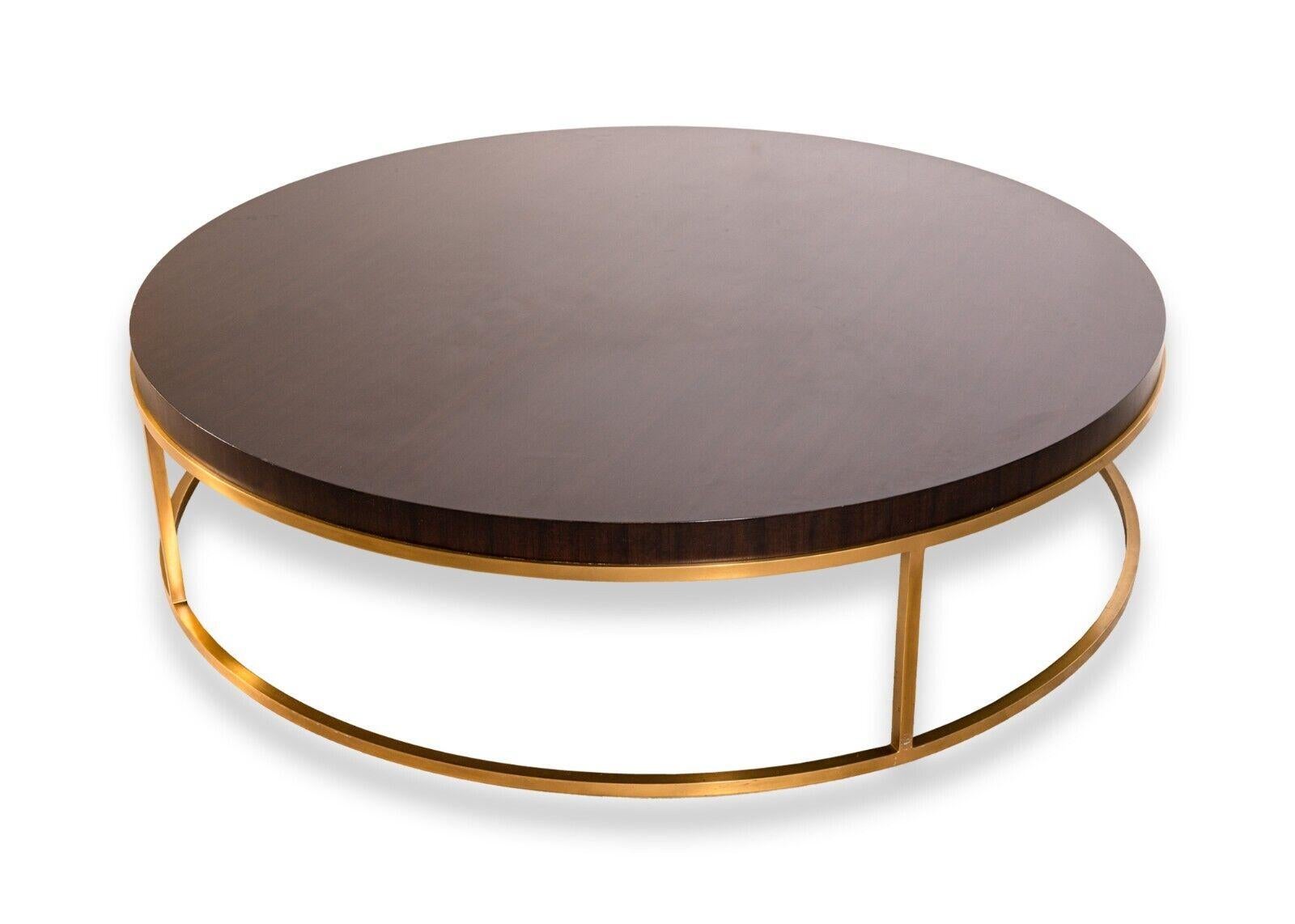 A large round dark wood and brass coffee table. A lovely modern contemporary coffee table with a big presence. This coffee table from Restoration Hardware features a thick, round dark wood table top with a semi gloss finish, and a wrapped brass
