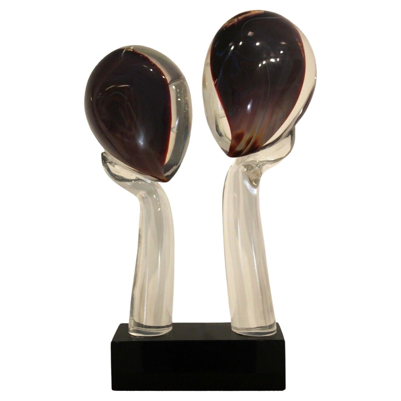 From Le Shoppe Too in Michigan this brilliant glass figurative sculpture, abstract in nature, represents two faces leaning on hands. Inlaid colors on the reverse give this sculpture a variety of tones and shades. Inscribed signature on base. by the