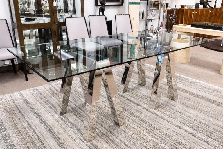 A pace style polished chrome glass dining room table with a chrome sawhorse base. This dining room table is in very good vintage condition. The glass is in very good condition with minimal scratches and only one small chip on the underside edge of