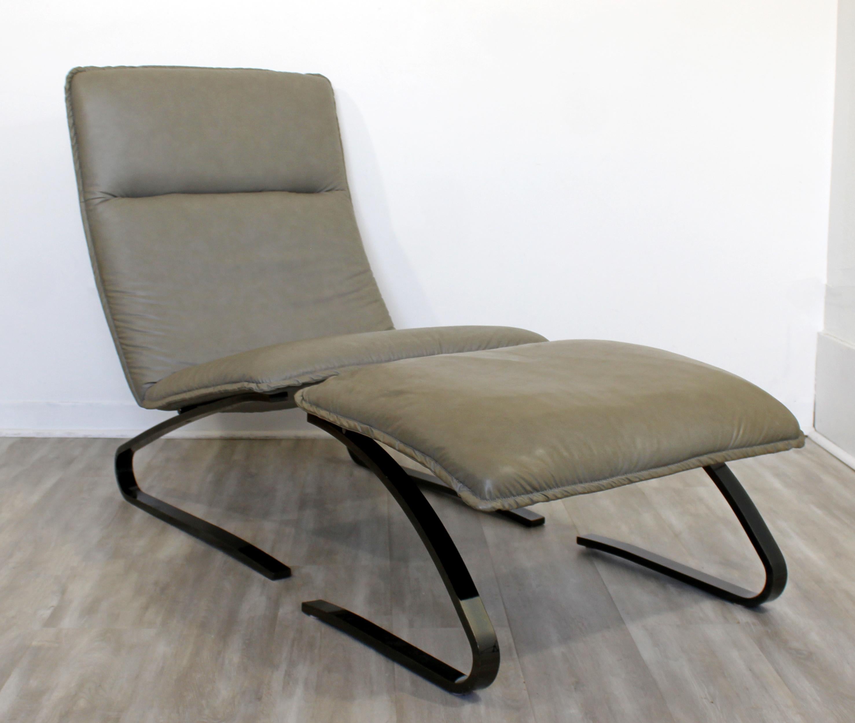 For your consideration is a luxurious, gray leather upholstered lounge chair on a gummetal base, with a matching ottoman, by The Design Institute of America, circa 1990s. In excellent condition, with slight wear to the upholstery. The dimensions of