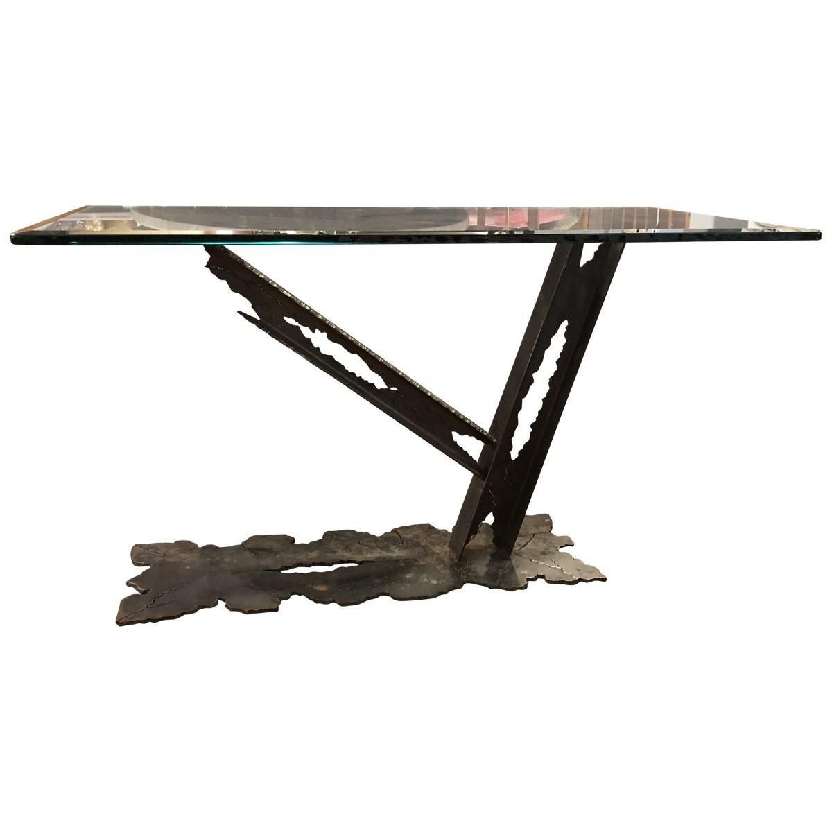 This contemporary modern sculptural studio console table is a sleek and edgy piece that will look great in the eclectic, contemporary space. This handcrafted sculptural steel console table features a base with jagged edges with a rectangular thick