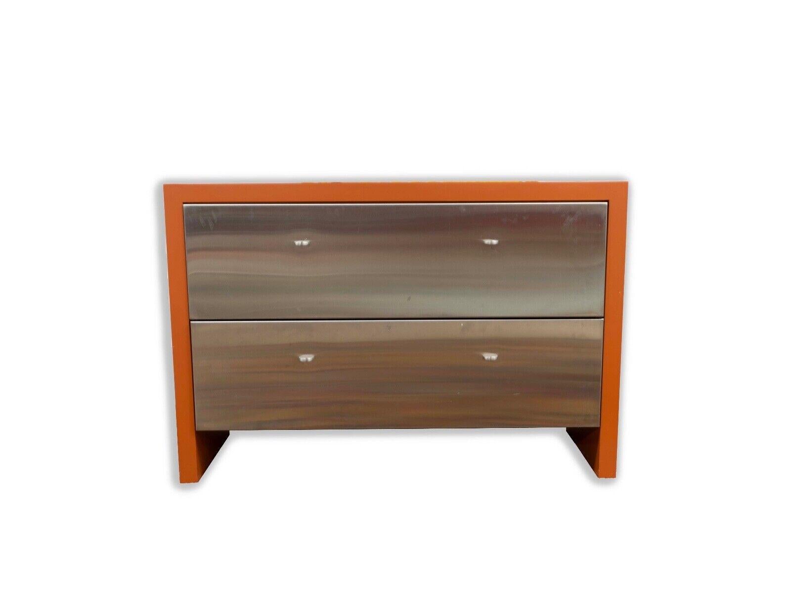 This contemporarymodern dresser boasts a striking combination of stainless steel drawers encased in a vibrant orange lacquer frame, exuding a retro yet contemporary charm. The piece's clean lines and contrasting colors create a bold statement, while