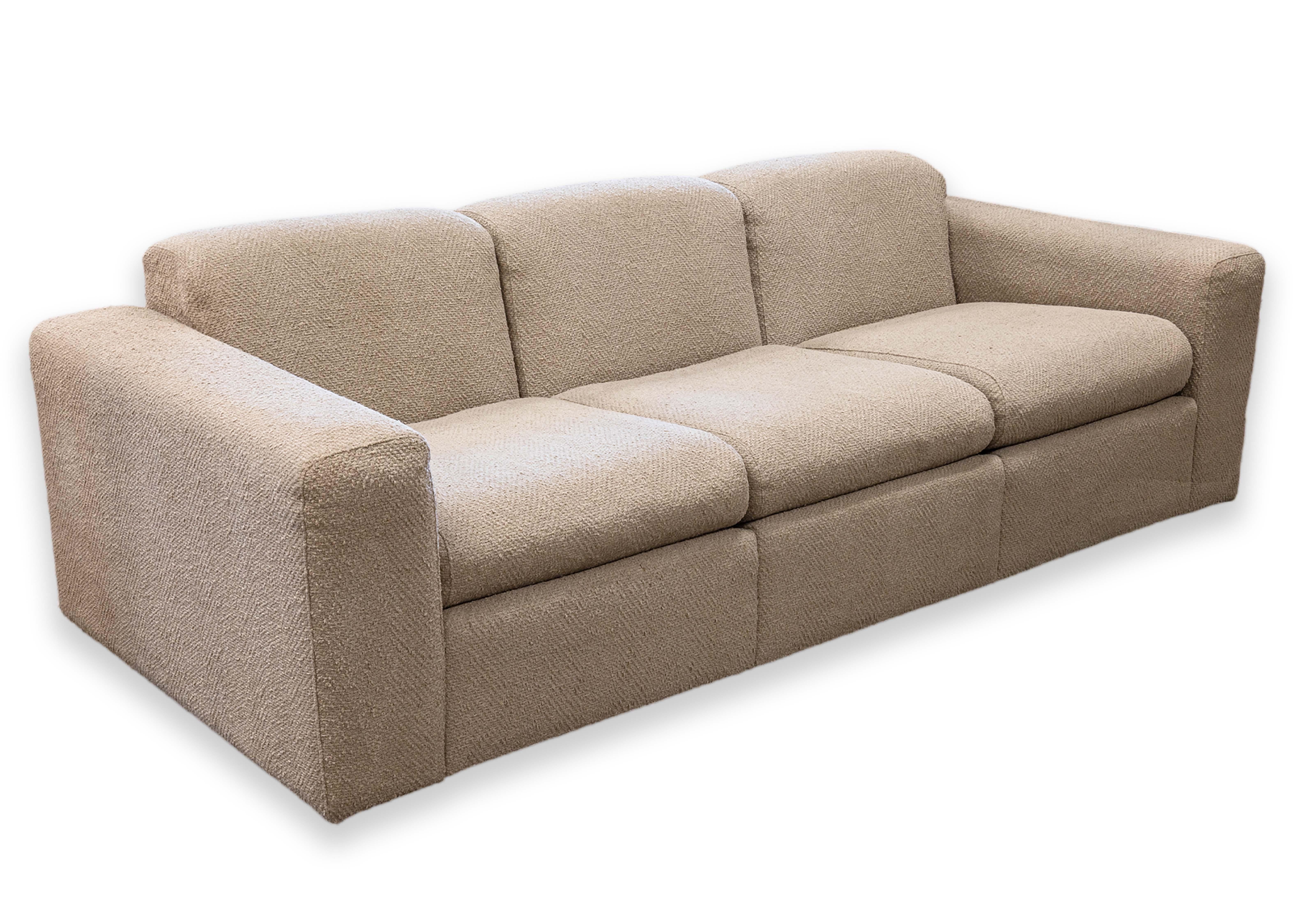 A Jack Cartwright style sofa. This contemporary modern sofa is upholstered in a beautiful and simple beige boucle style fabric. This luxe sofa is very comfortable and plush, but firm enough to support you. This piece has a very simple, but lovely