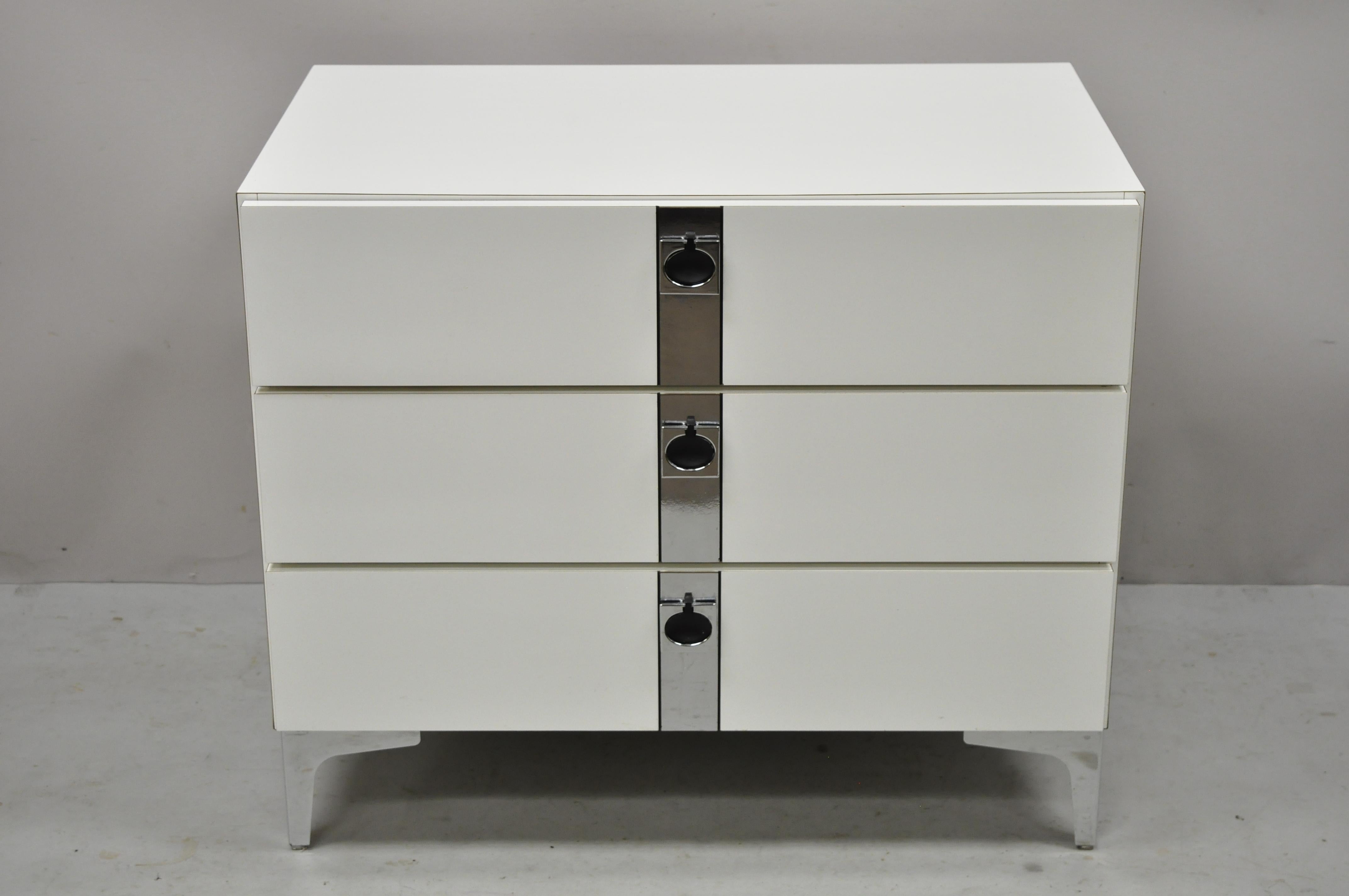 Contemporary Modern white Formica chrome trim 3 drawer chest nightstand bedside table. Item features chrome trim and feet, white formica wrapped case, 3 drawers, clean modernist lines, great style and form. Circa 21st century, Pre-owned.