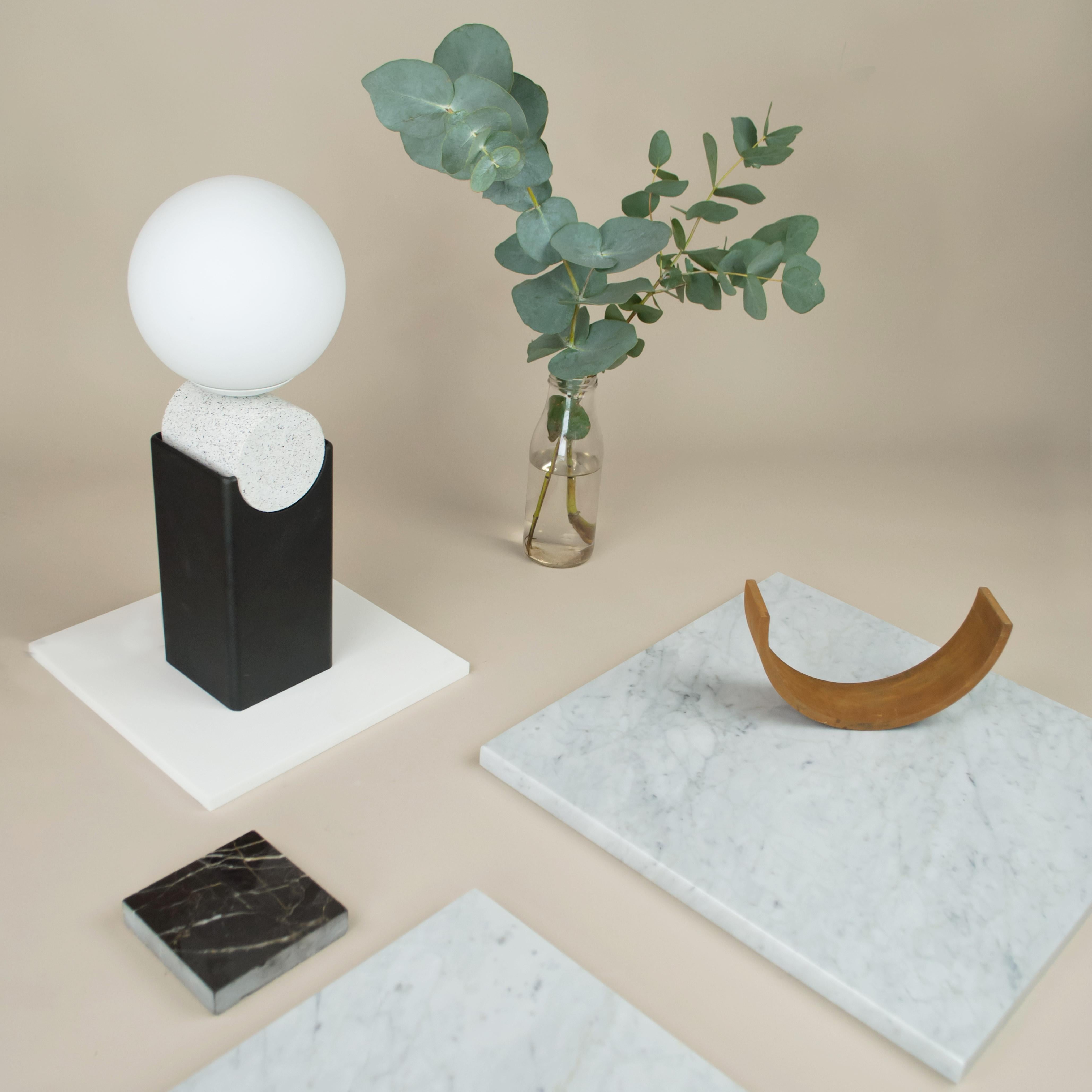 Monument Lamp - Circle Version 2 has a blackened steel base with a cast stone cylinder and a matte opal glass globe. 

The Monument Lamp V2 is handmade in Jobst’ studio in east London. Jobst’ research into historical monuments and their relationship